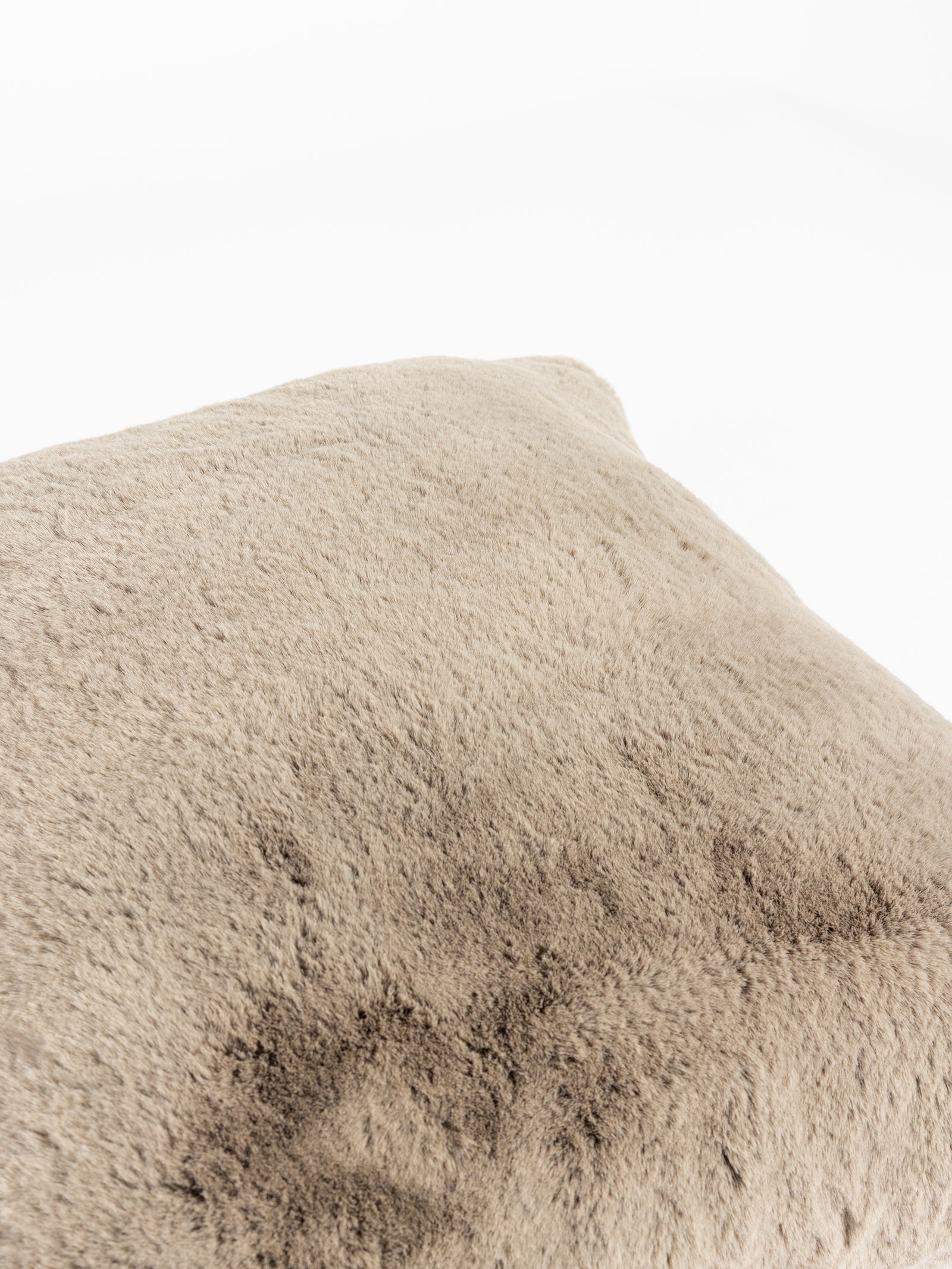 A close-up image of the Cuddle Pillow by Cozy Earth, showcasing its soft beige plush surface and fuzzy texture. The pillow dominates the frame, highlighting its smooth and cozy design against a plain white background. 