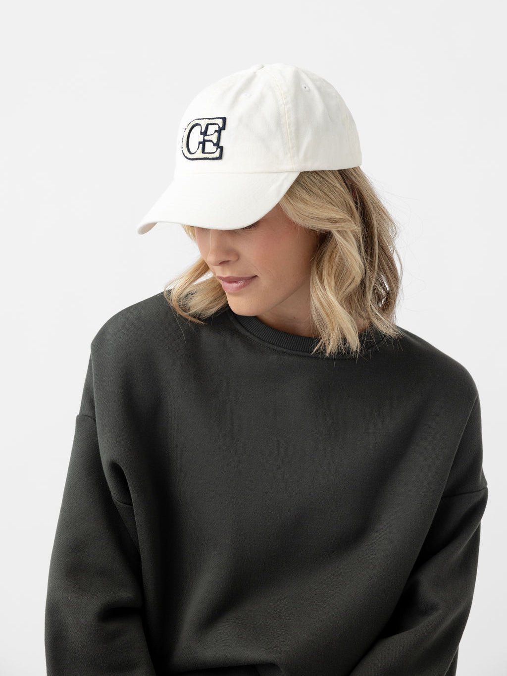 Woman looking down wearing washed cream vintage cap 