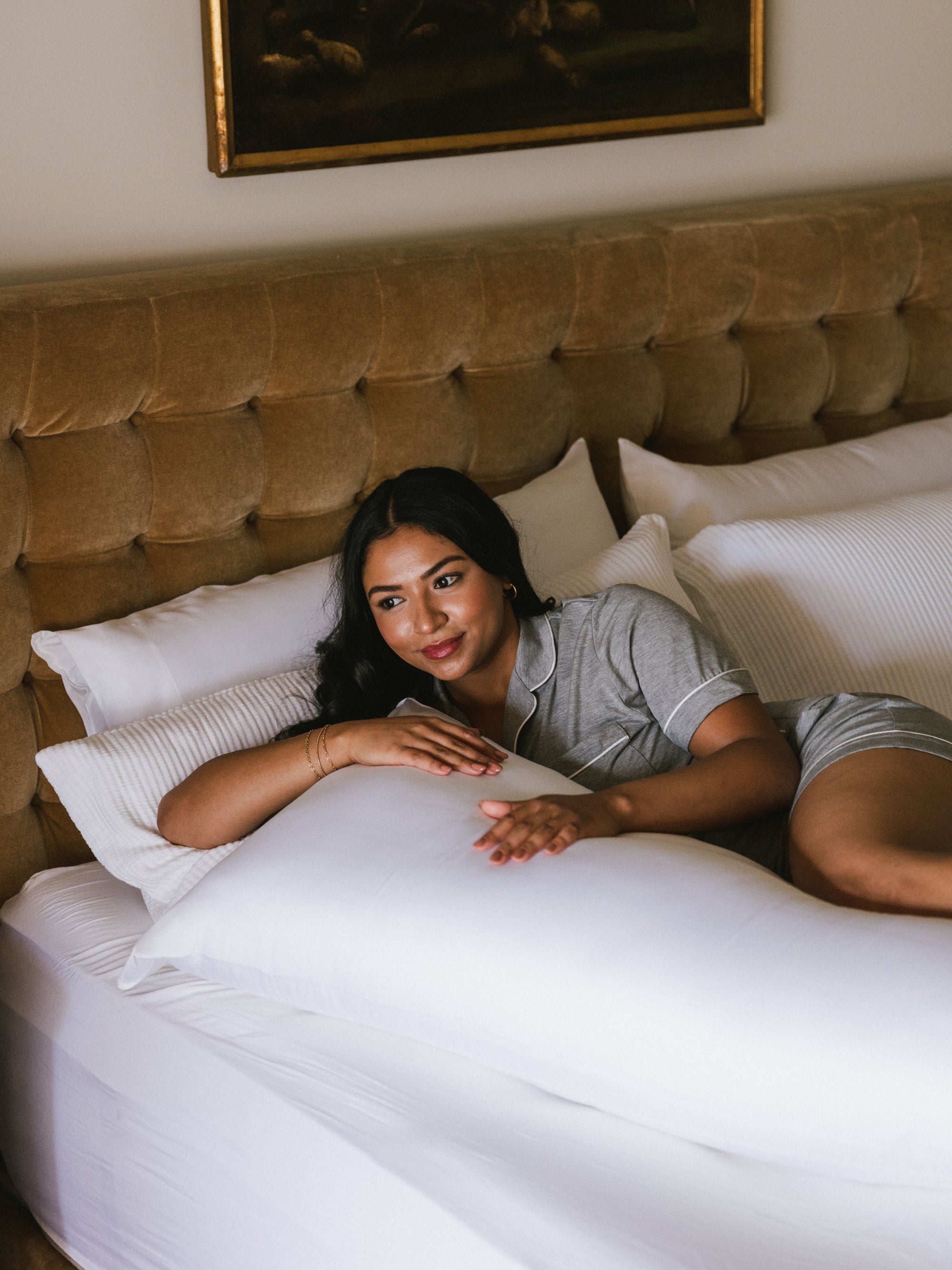 Woman laying in a bed with white body pillow 