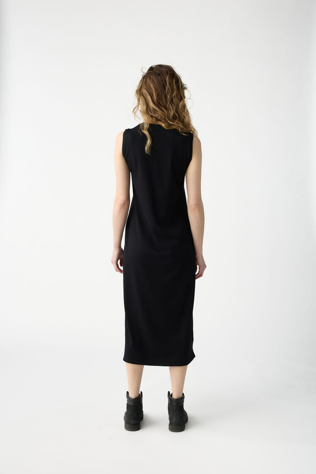 Rear view of a person with wavy hair wearing a Cozy Earth Women's Brushed Bamboo Sleeveless Midi Dress and dark boots, standing against a plain white background. 