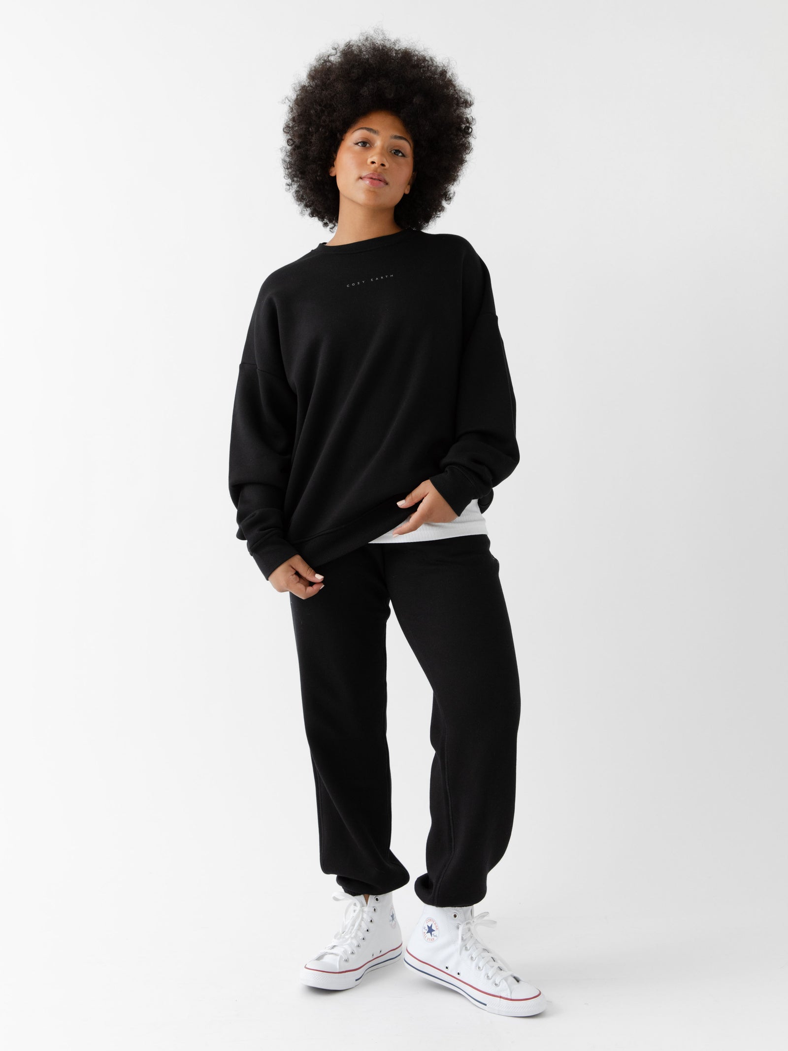 Black CityScape Joggers. The Joggers are being worn by a female model. The photo is taken with the models hand by the pocket of the joggers. The back ground is a crisp white background. 