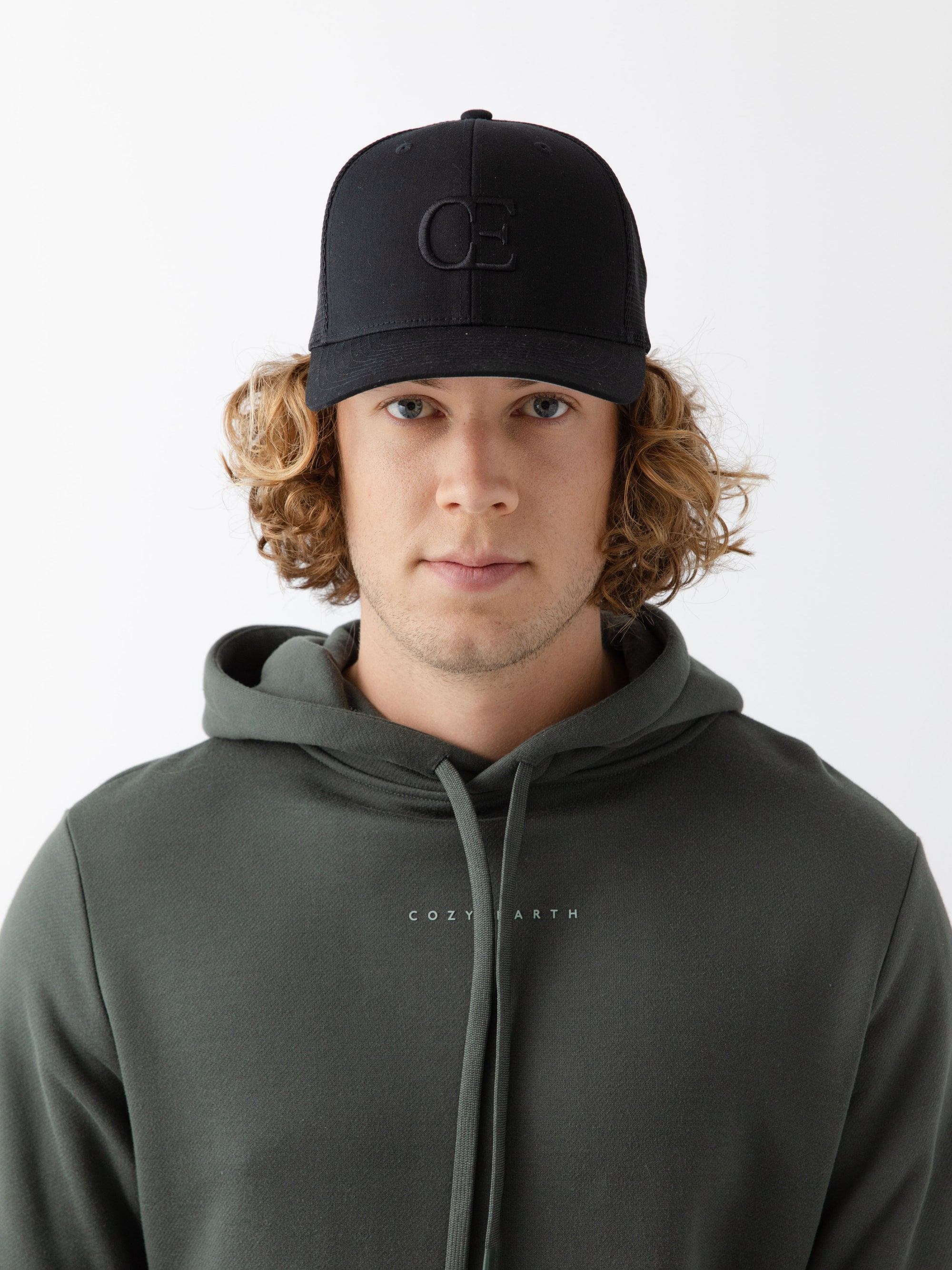 Man wearing a black cap with a CE logo on a light gray background 