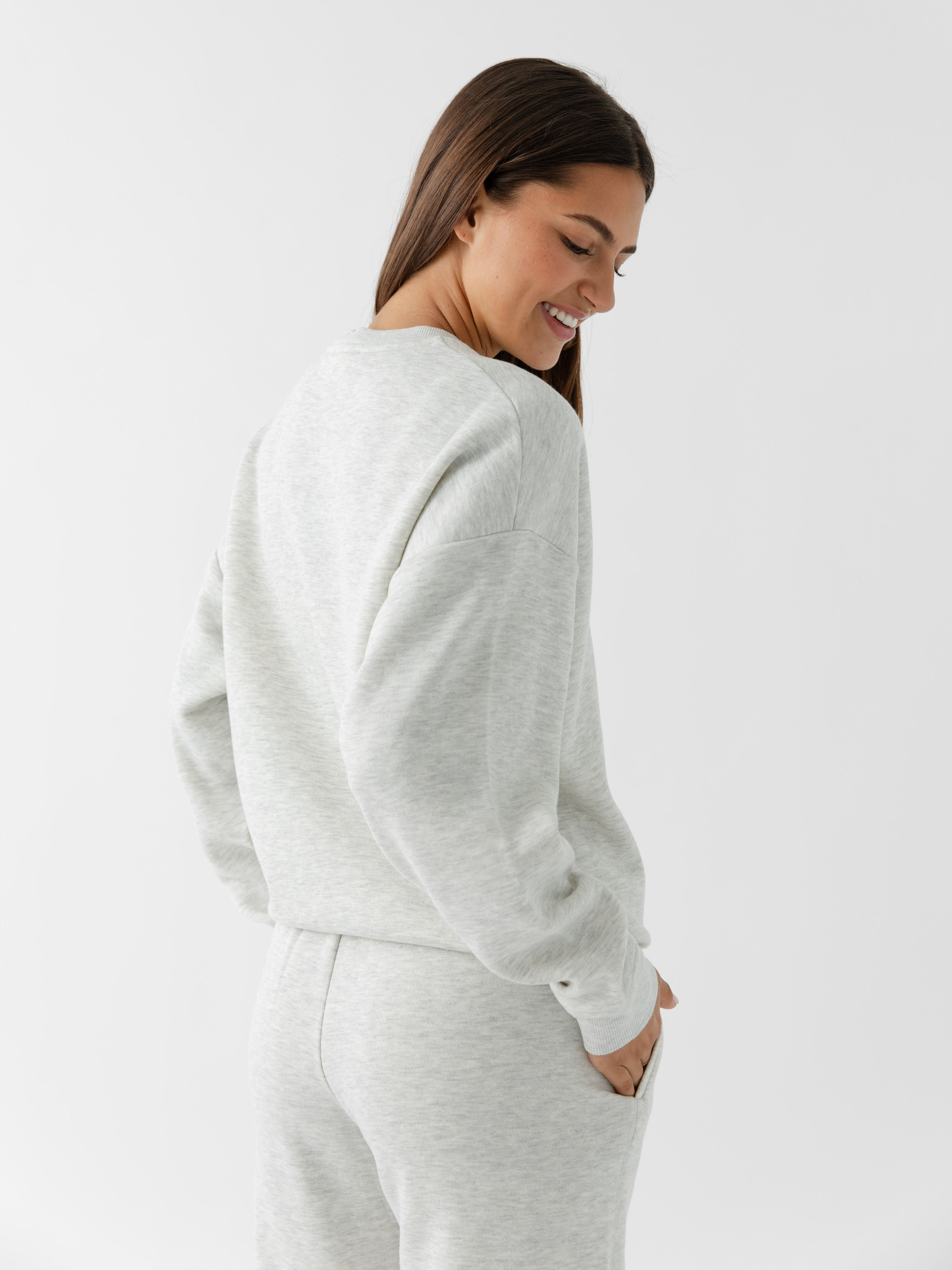 Heather Grey CityScape Pullover Crew. The Pullover is being worn by a female model. Accompanying city scape clothing is being worn to complete the look of the outfit. The photo was taken with a white background. 