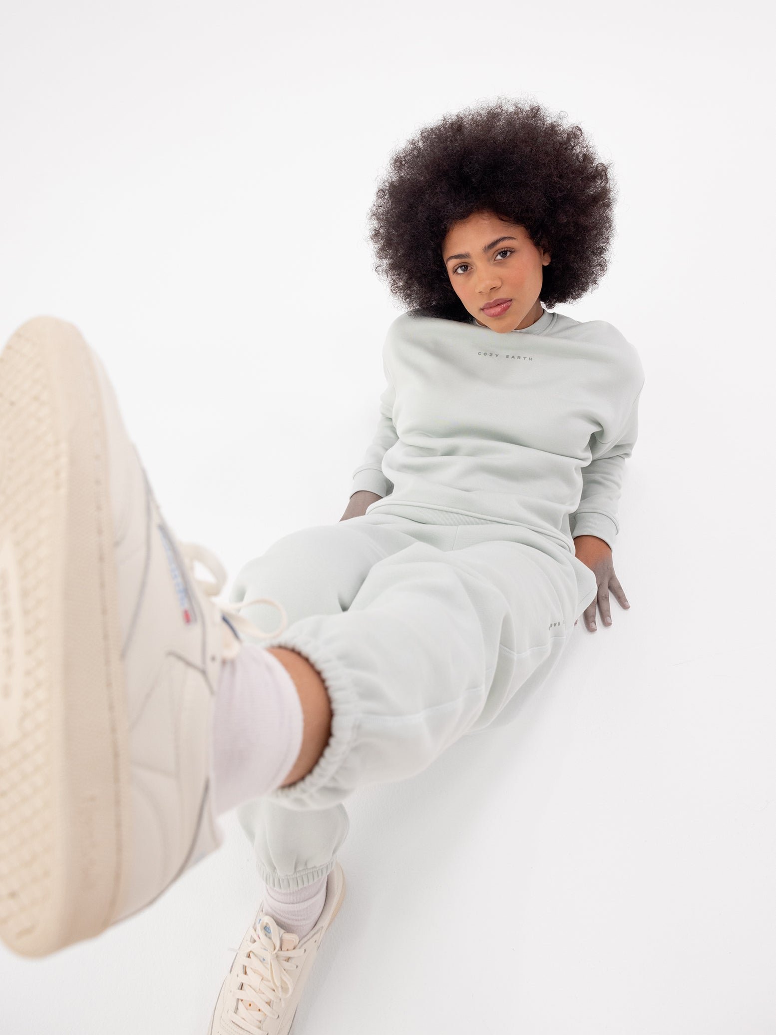 Woman in arctic cityscape set sitting on ground with foot up 