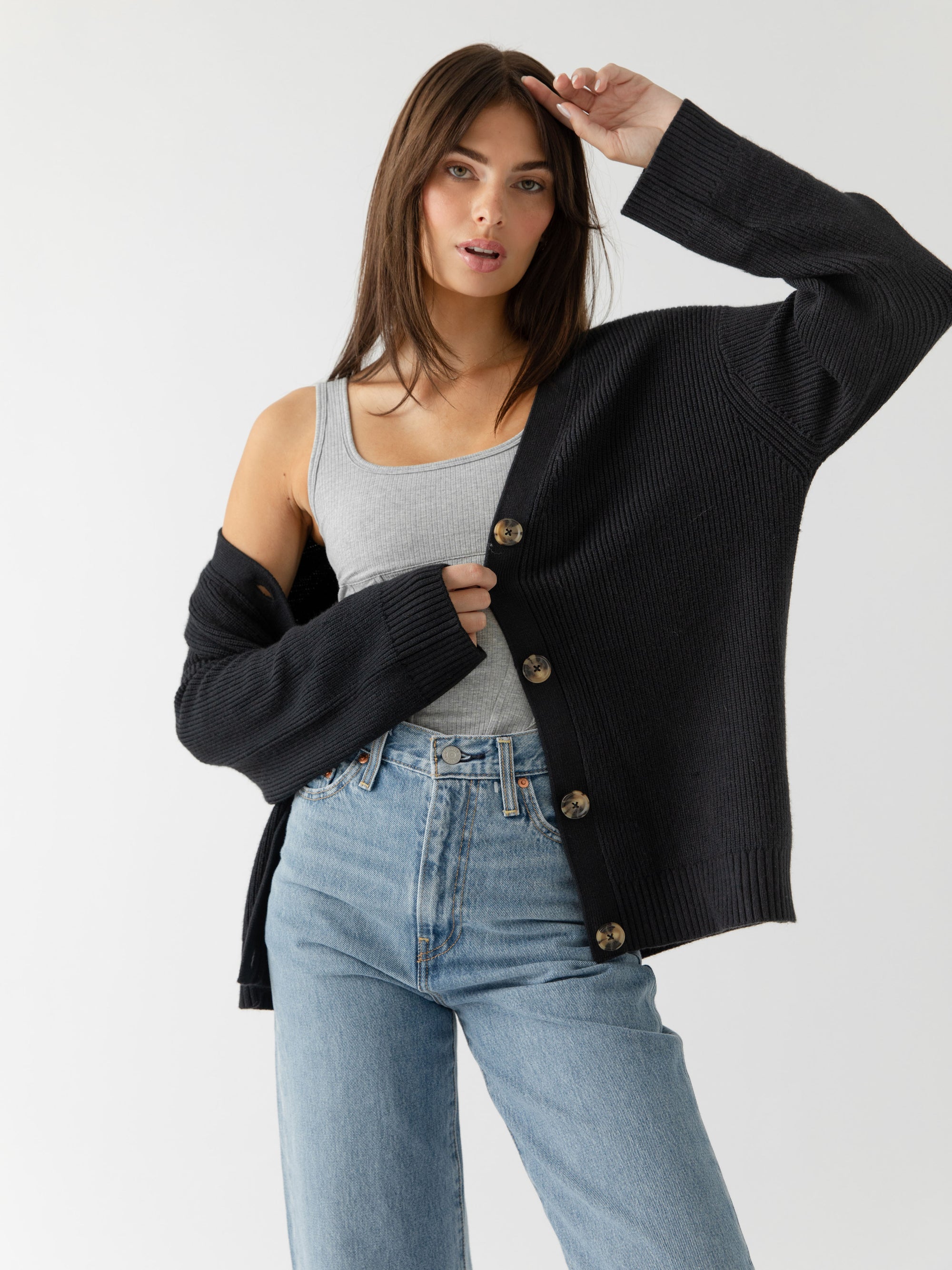 A woman wearing Cozy Earth Classic Cardigan in Black stands in front of a white background 