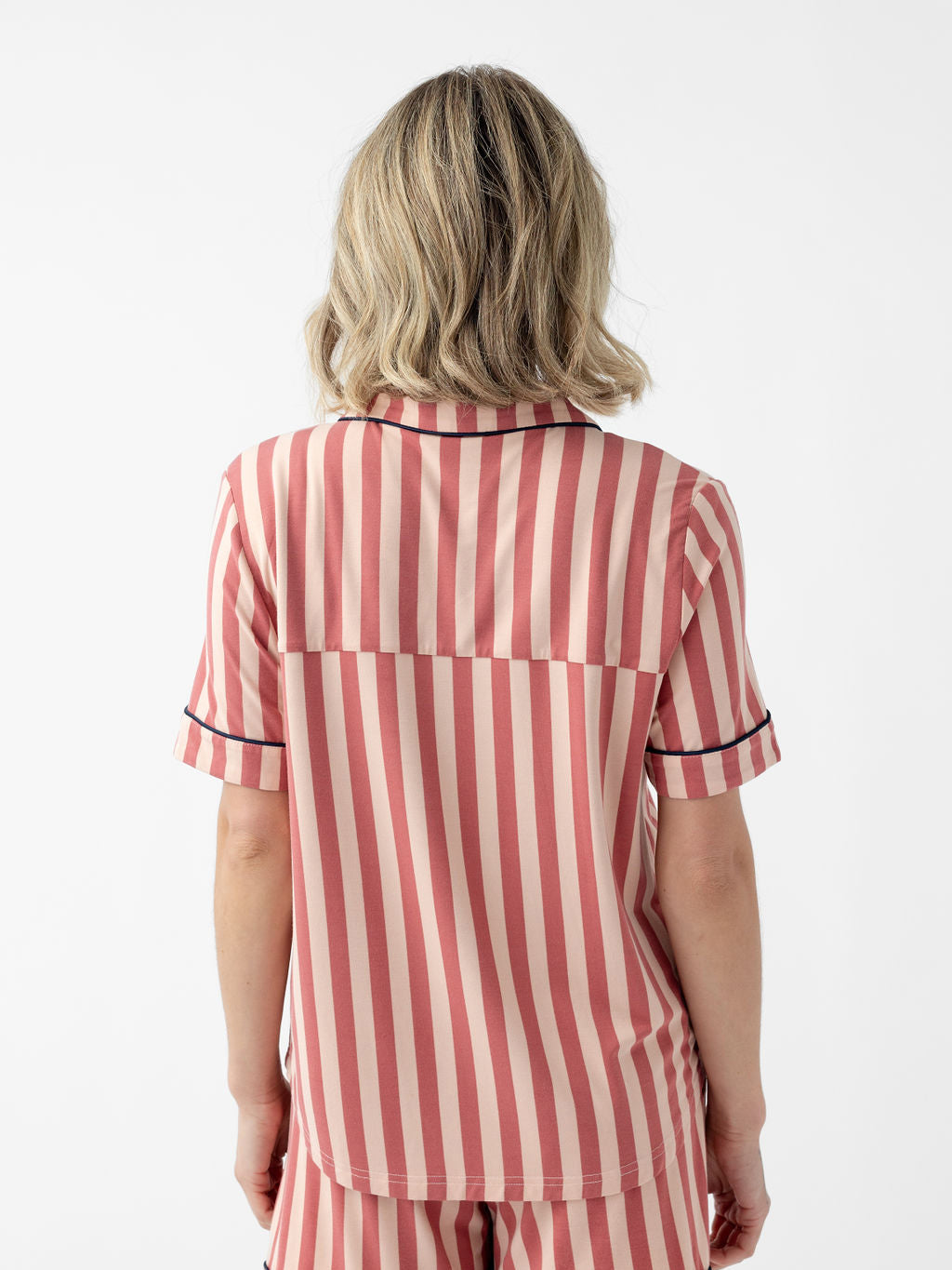 Back of woman wearing blush stripe short sleeve pajama top with white background 