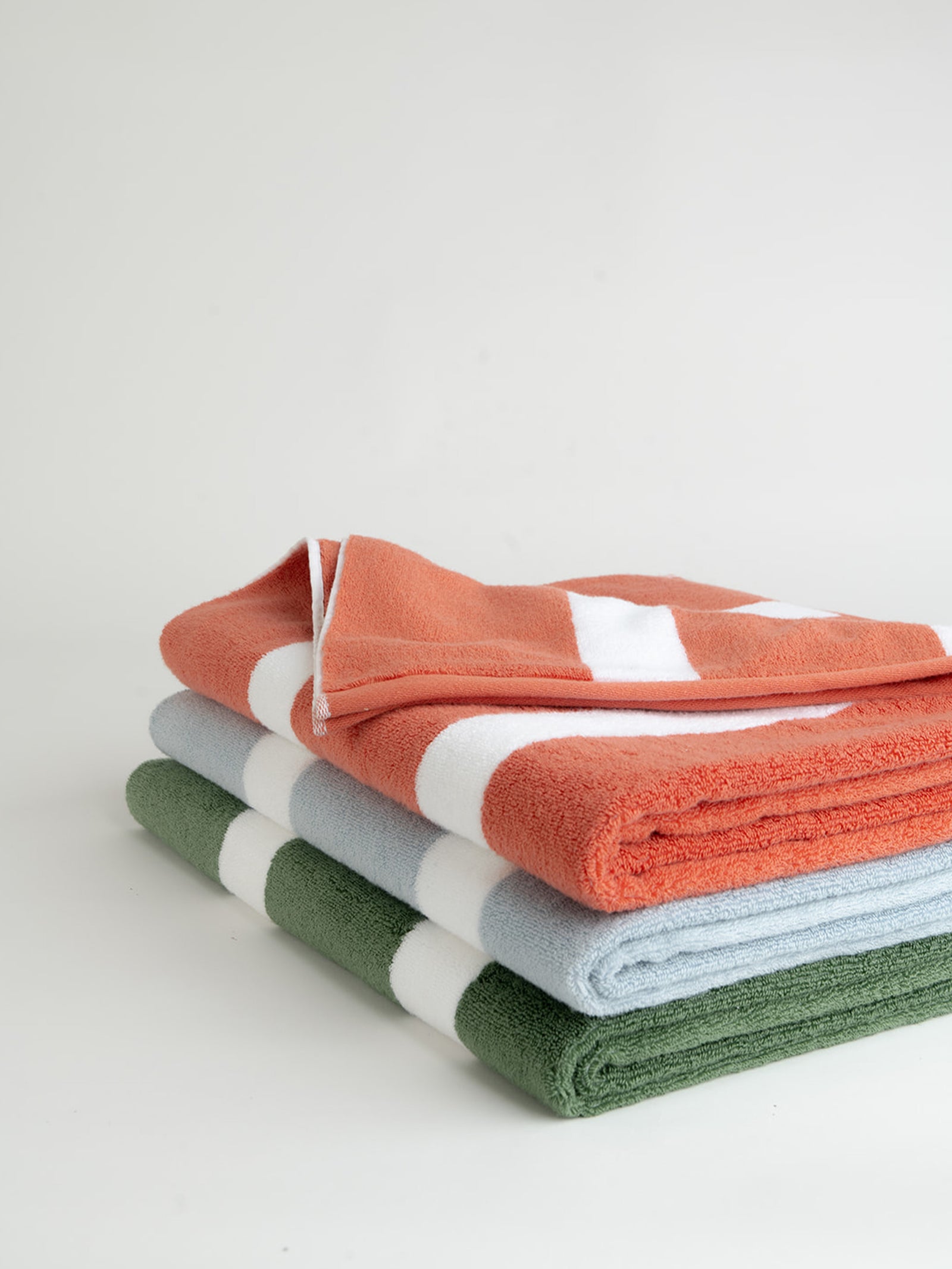 Breeze, Coral, and Sage Stripe resort towels folded with white background