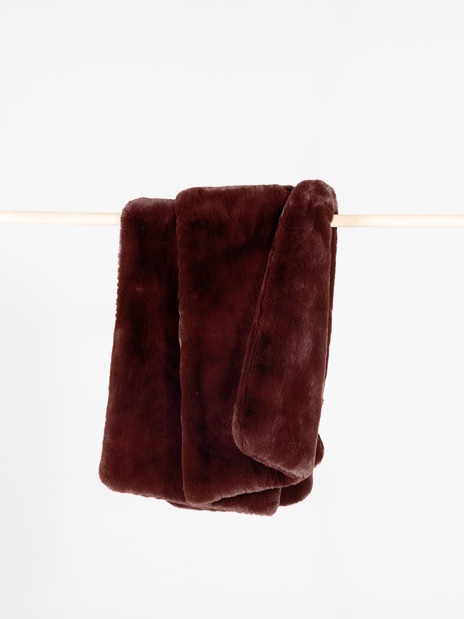 Burgundy oversized throw cuddle blanket draped over a wooden pole