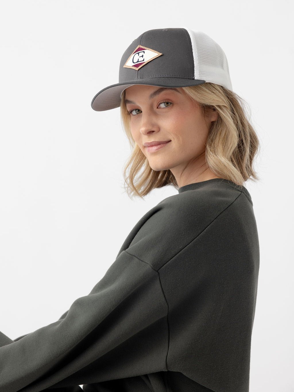 Woman looking at camera wearing charcoal/white diamond mesh trucker hat 
