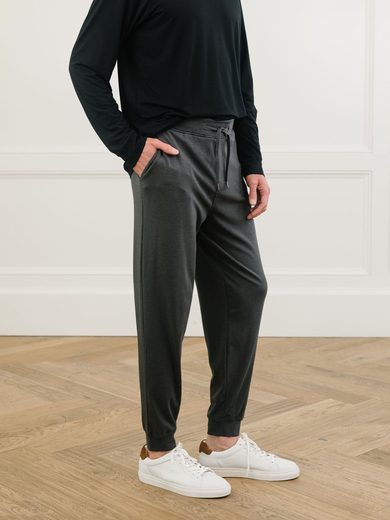 Black/Charcoal Men's Bamboo Jogger Set. There is a man wearing the jogger set. He is standing in a well lit room in a home.