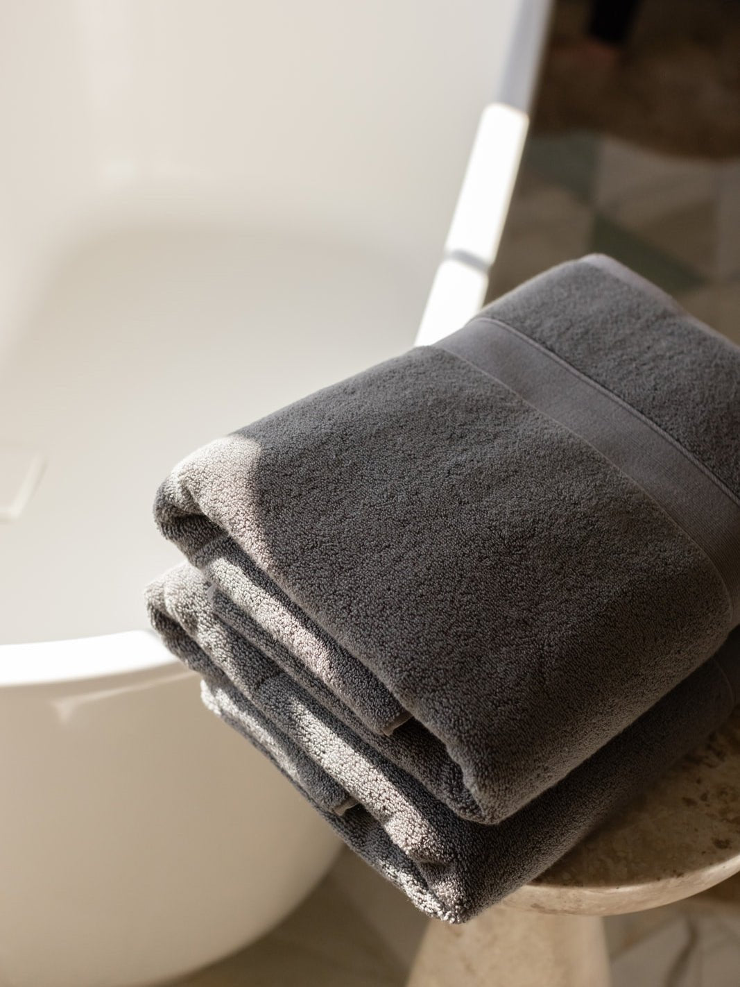 Folded luxe bath sheets next to bathtub 