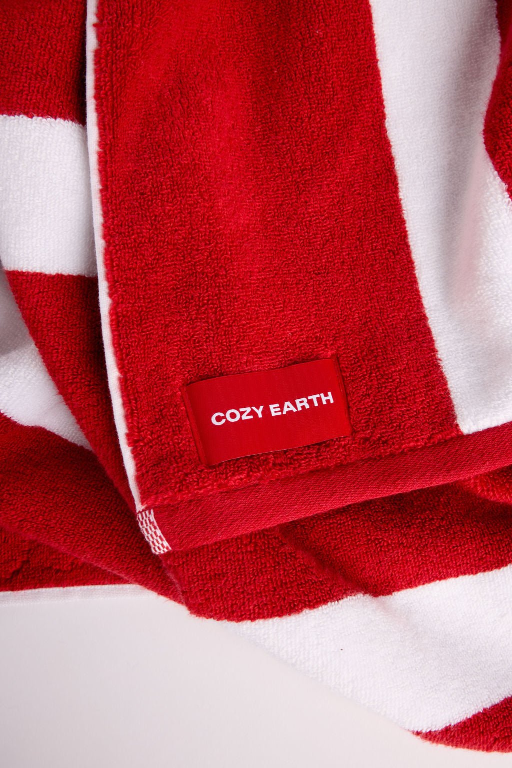 A red and white striped Classic Stripe Resort Towel by Cozy Earth featuring a red tag. 