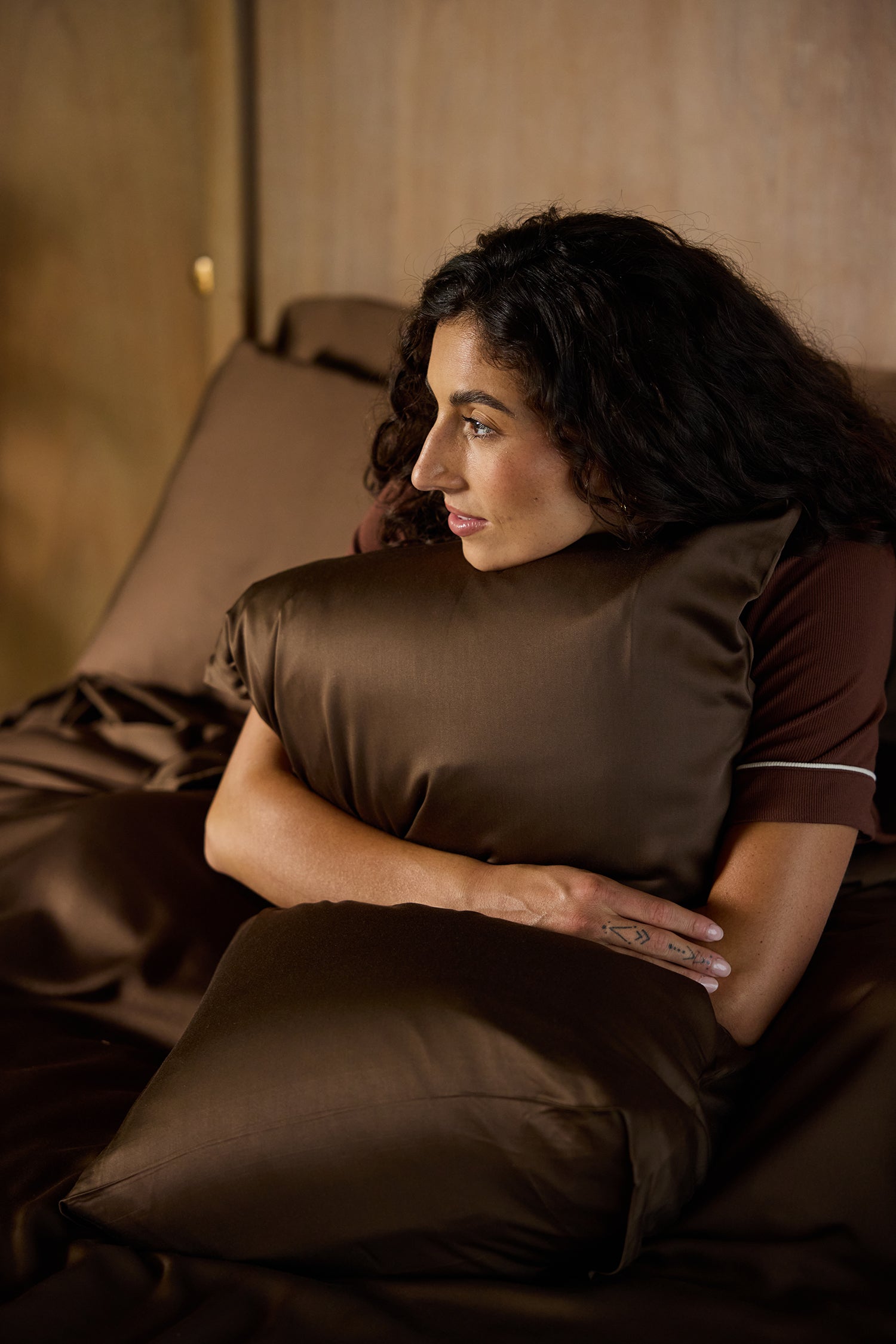 Woman sitting on bed holding pillow with coffee pillowcase standard/king/body