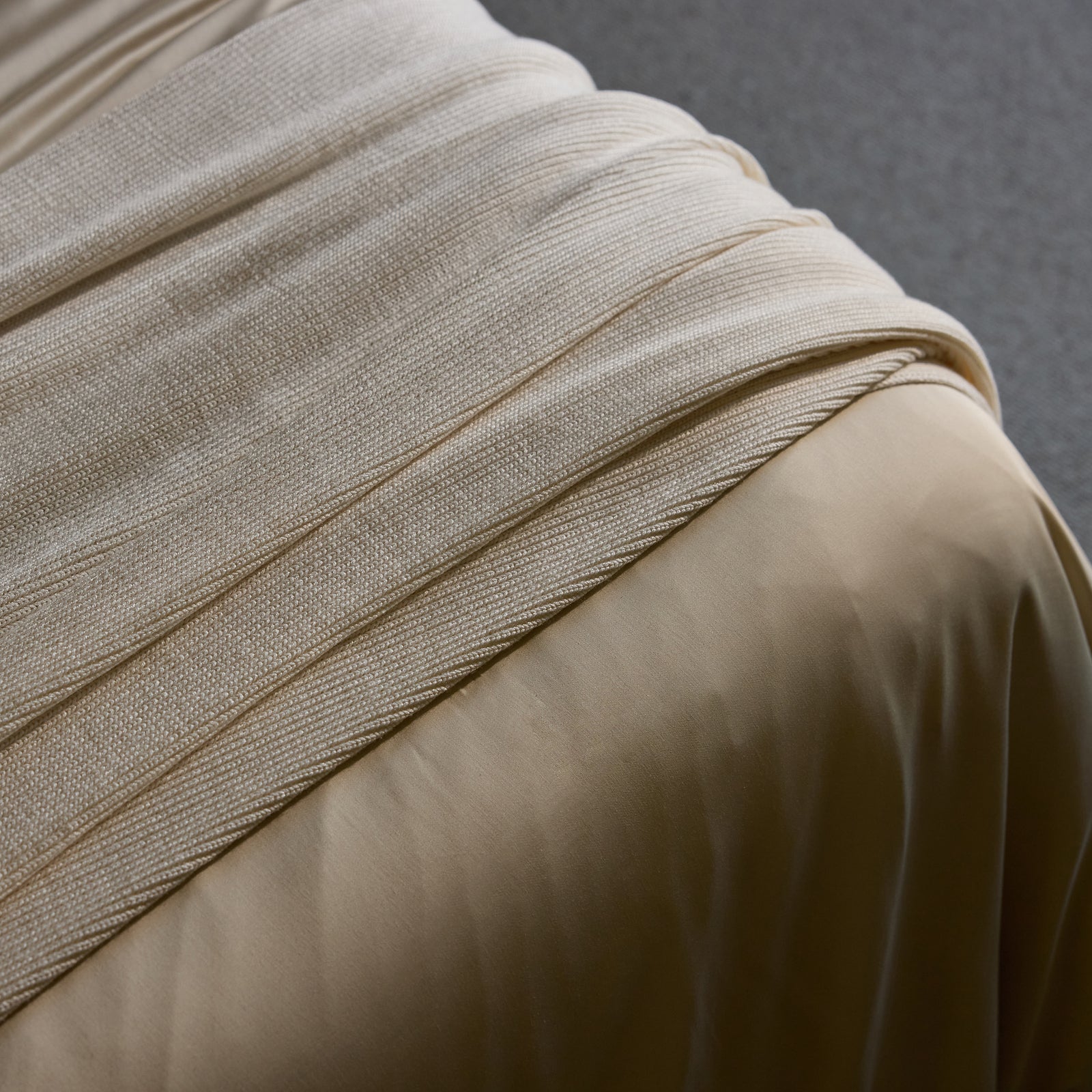 Creme Classic Knit Blanket draped over a bed. 