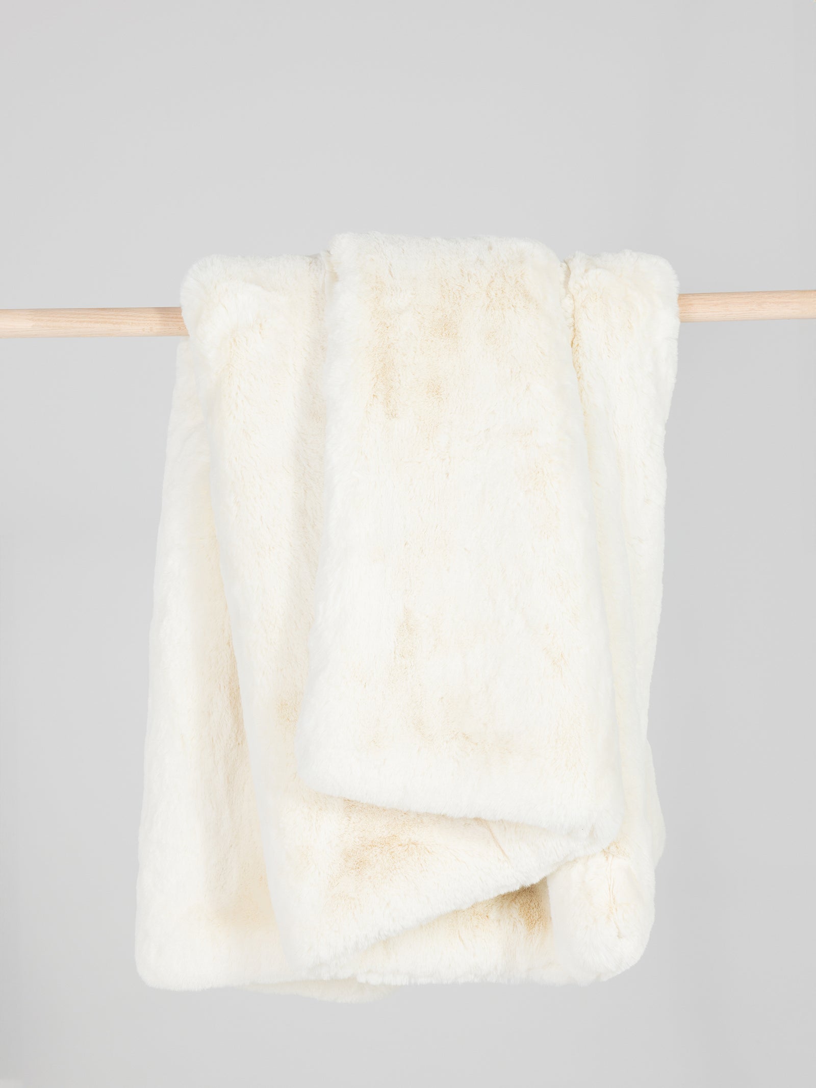 Creme oversized throw cuddle blanket draped over a wooden pole 