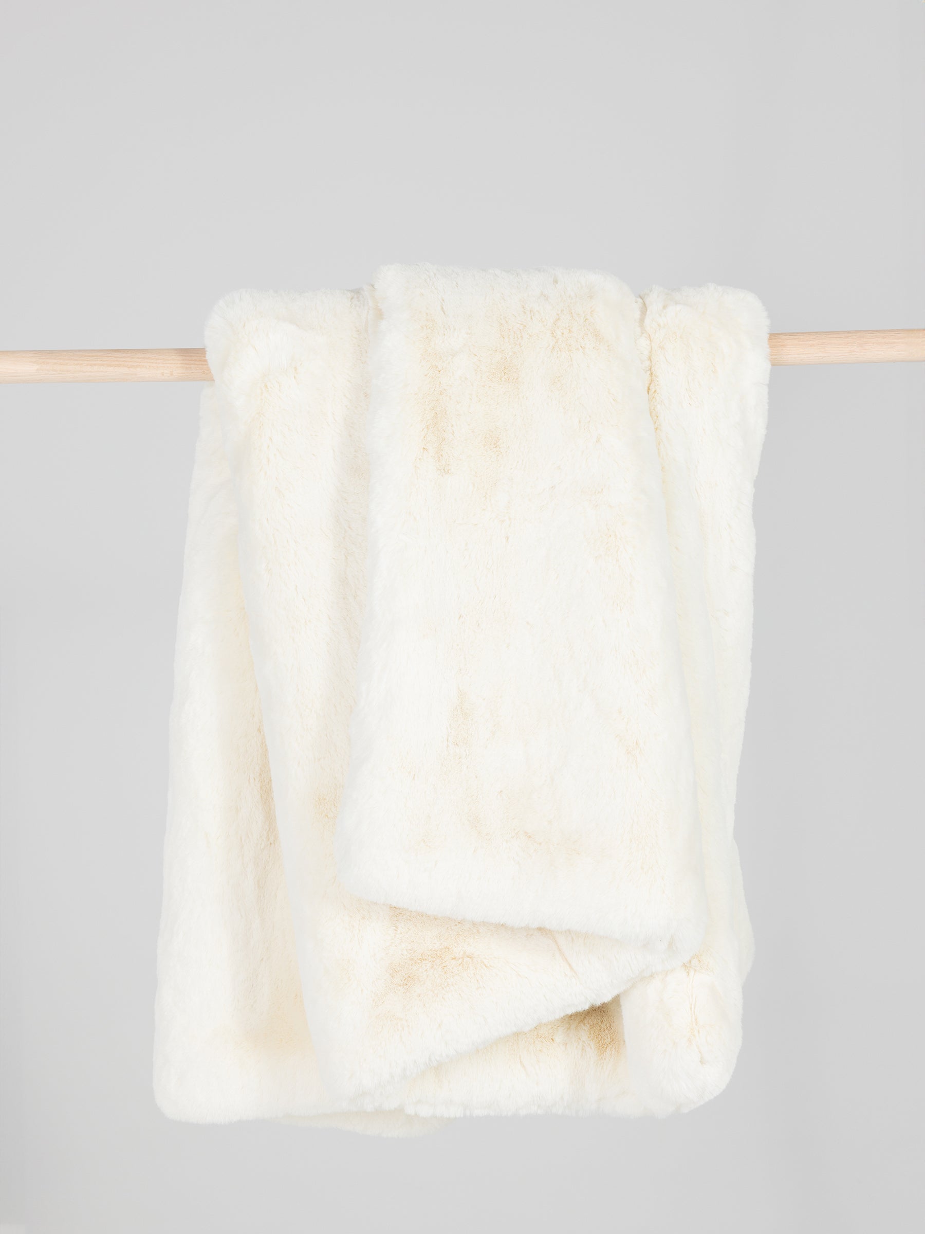 Creme oversized throw cuddle blanket draped over a wooden pole