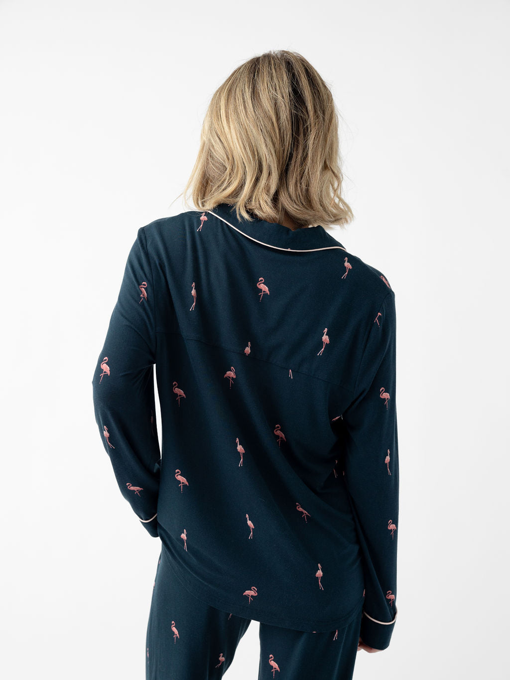 Back of woman wearing long sleeve flamingo print pajama top with white background 