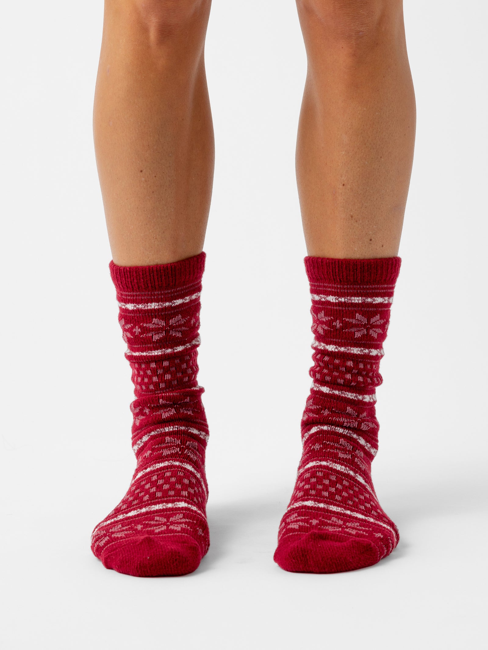 A person stands with a white background wearing Snowflake Plush Lounge Sock in Garnet 