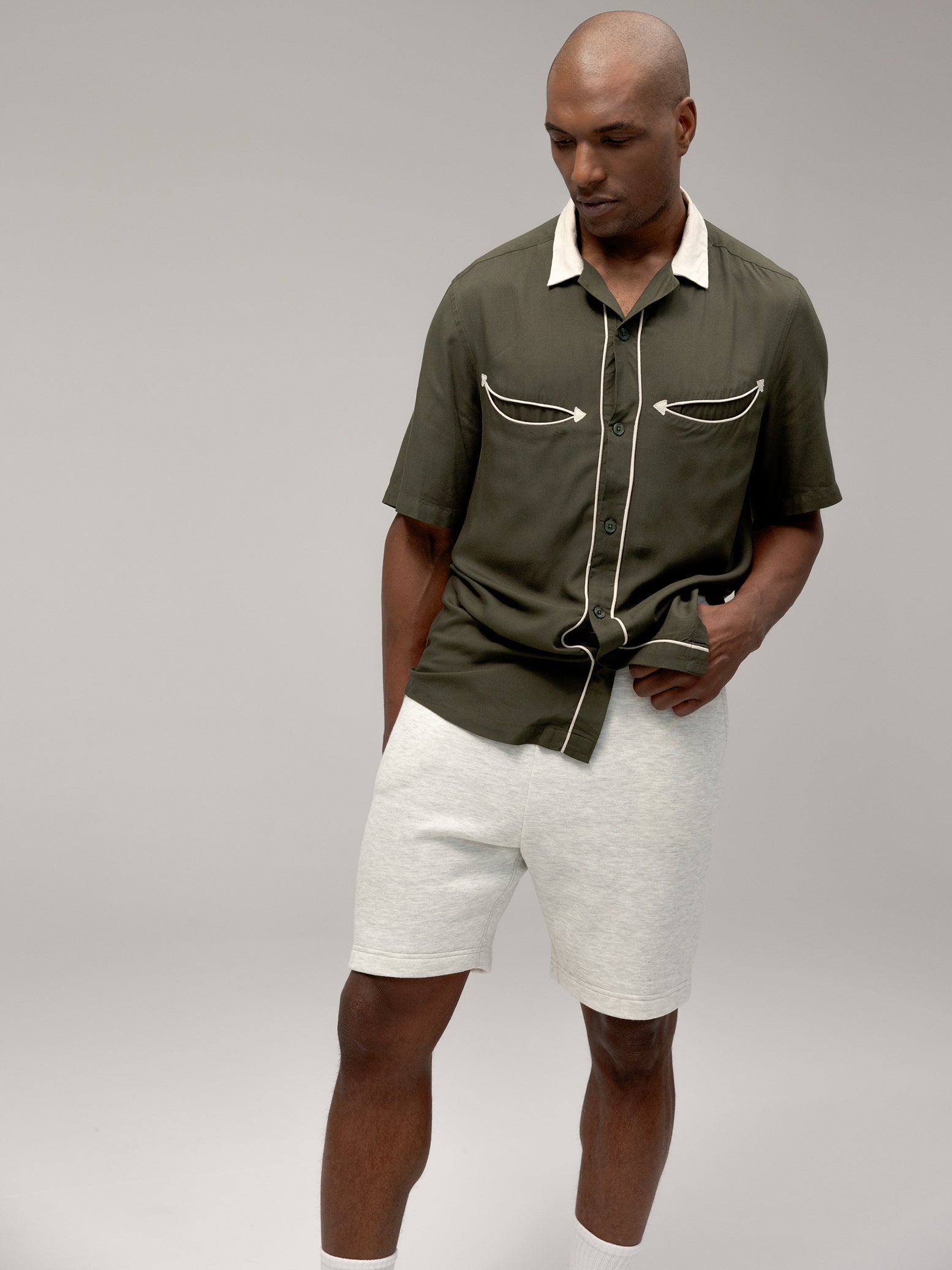 Man wearing heather grey cityscape shorts and dark green button down 