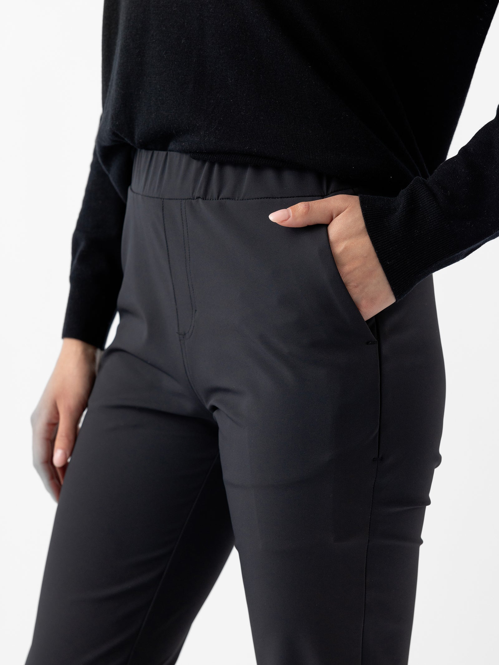 A person wearing Cozy Earth's Women's Always Cropped Pant and a black long-sleeve top, with their right hand placed in their pants pocket. The background is plain white, highlighting the clothing. 