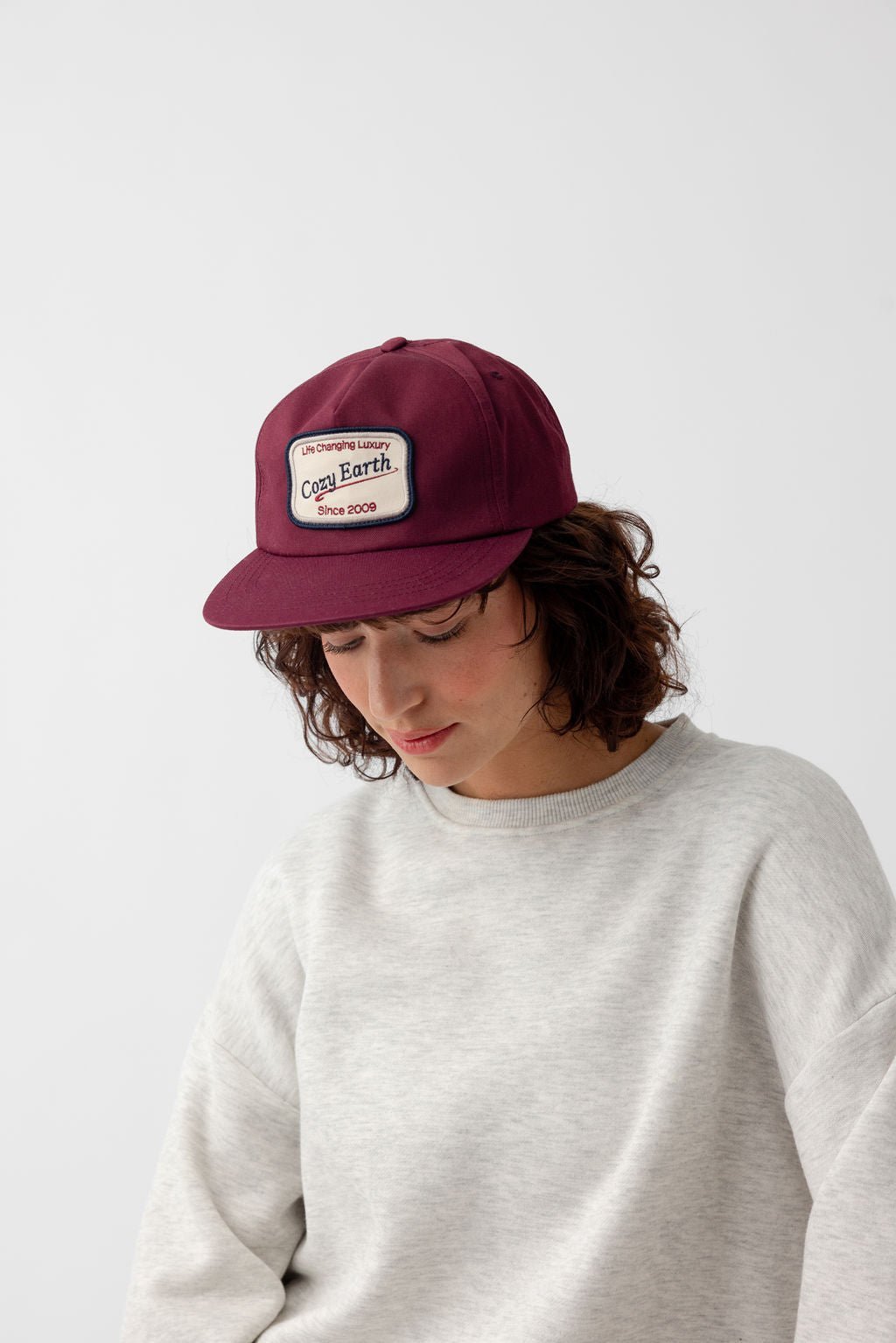 Woman looking down wearing maroon heritage snapback 