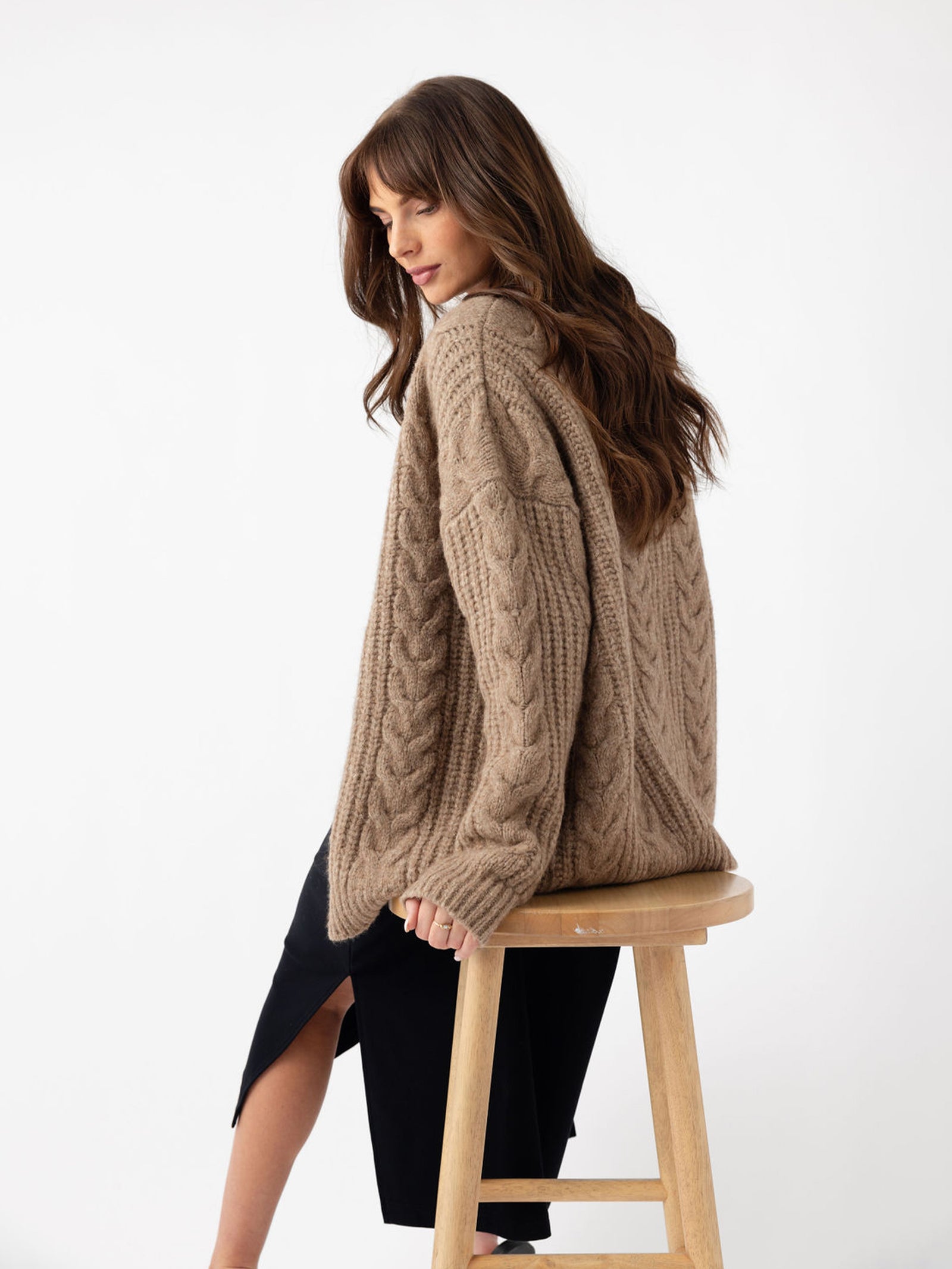 Back of woman sitting on wooden stool wearing mushroom cardigan 