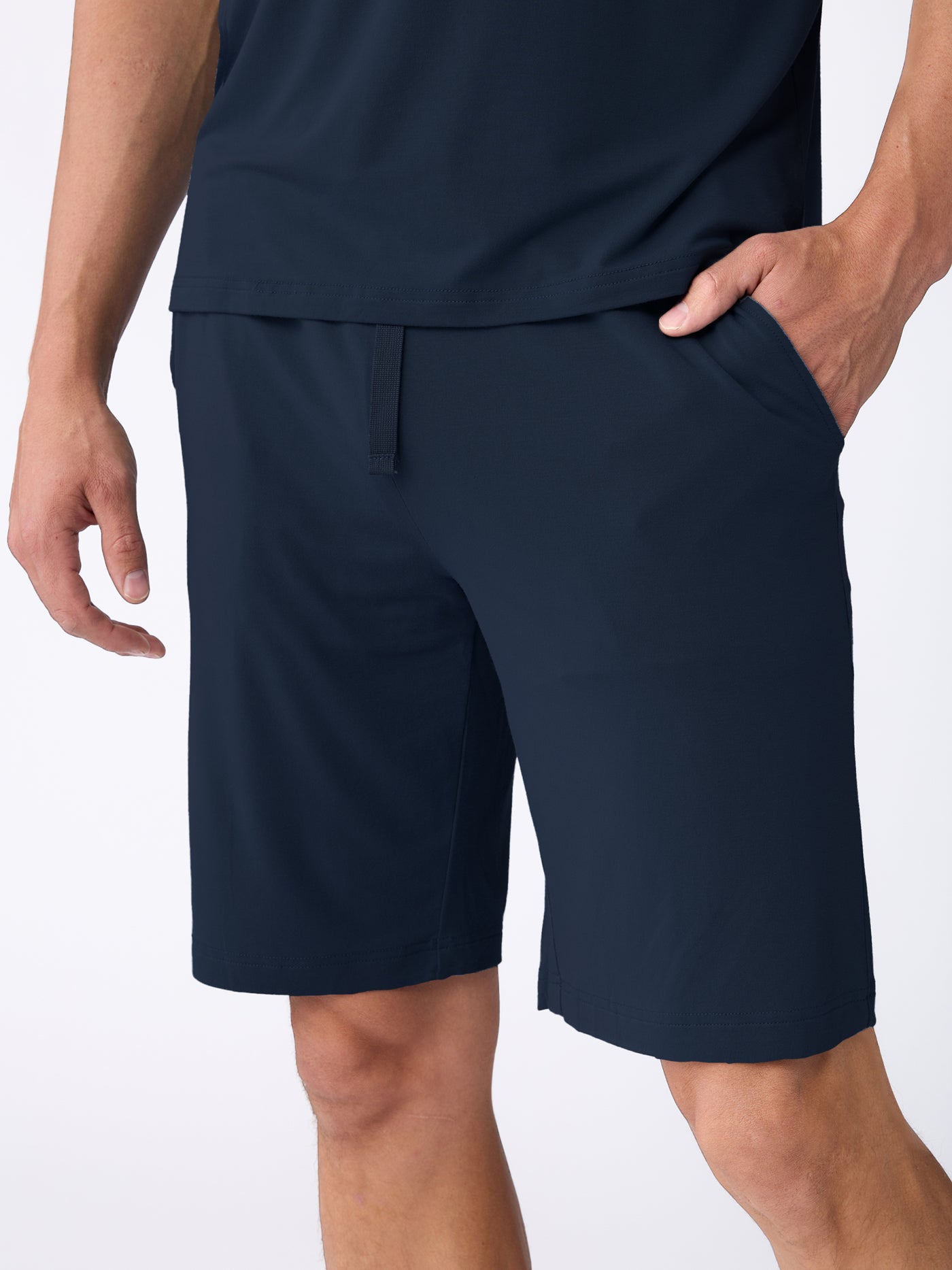 A person wearing the Cozy Earth Men's Bamboo Stretch-Knit Short Sleeve Pajama Set in navy, with one hand in their pocket. The image is cropped from the shoulders down, highlighting the comfortable  clothing. 