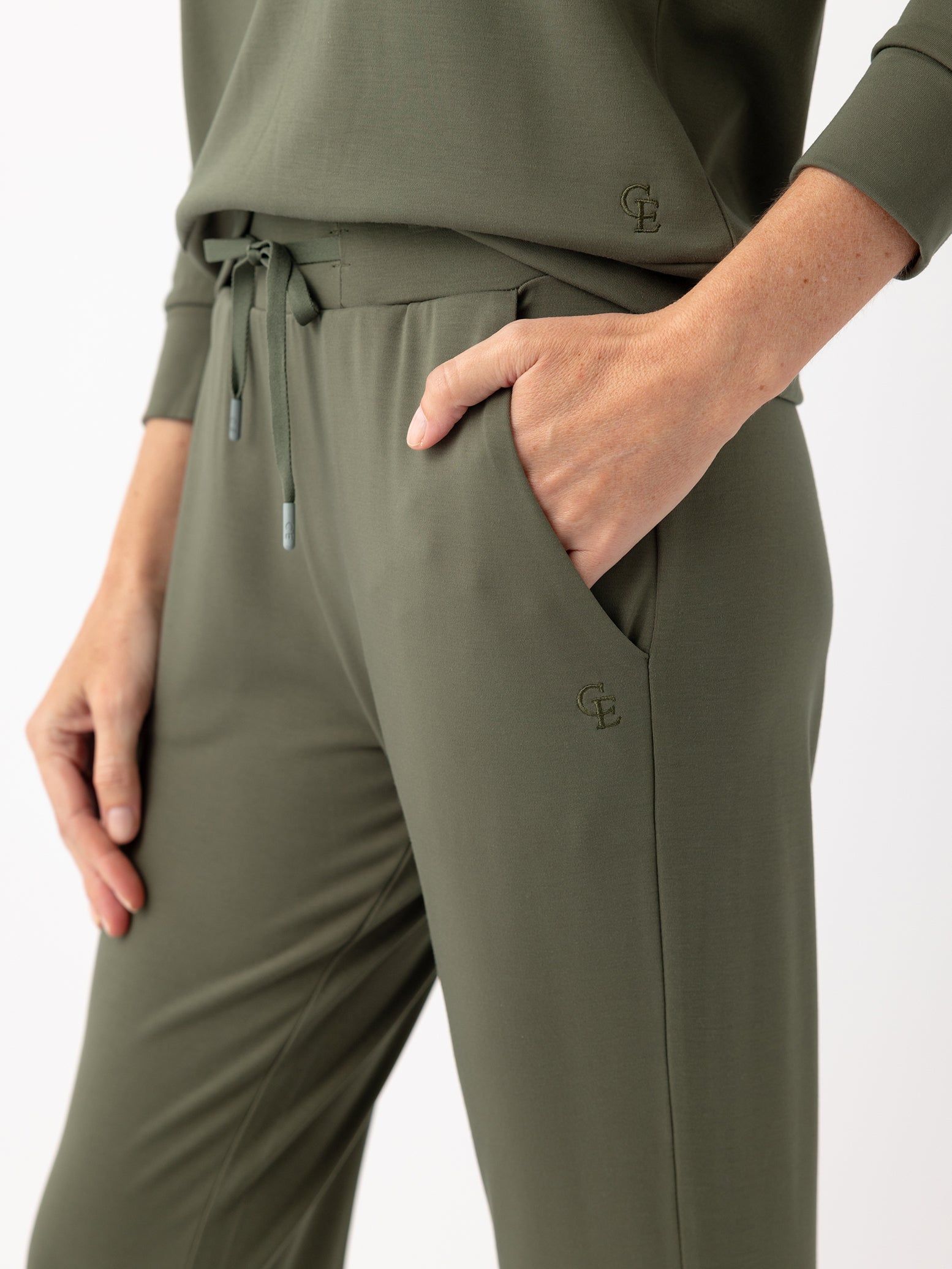 Close up of woman in olive joggers with white background 