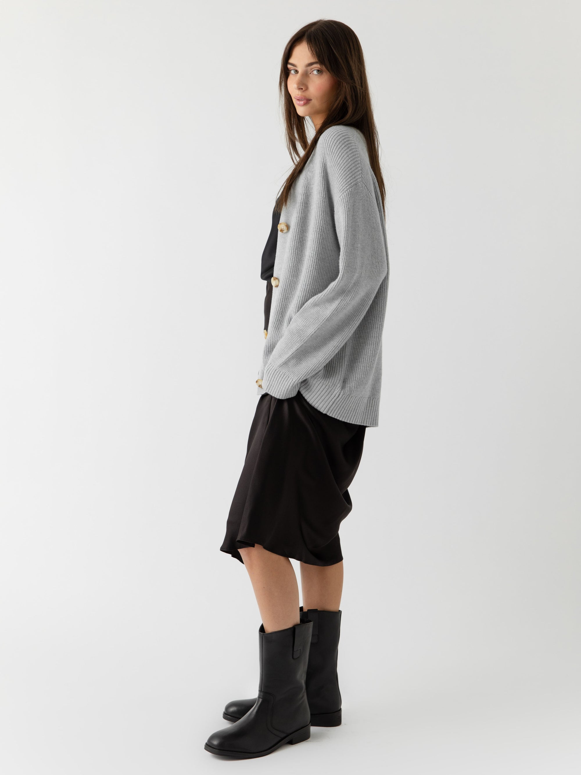 A woman wearing Cozy Earth Classic Cardigan in grey stands in front of a white background 
