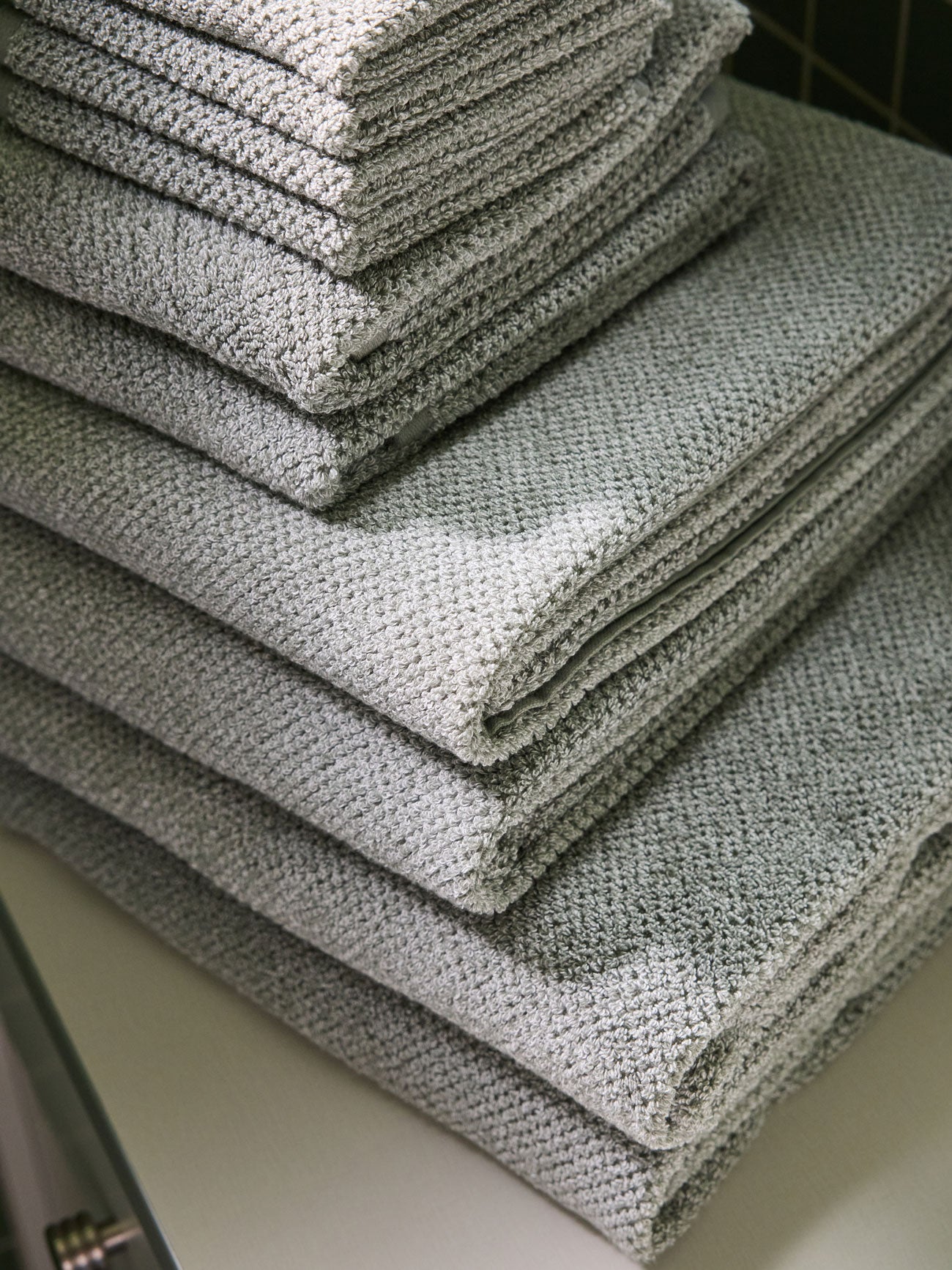 A stack of various sizes of Heathered Sage Nantucket Towels. 