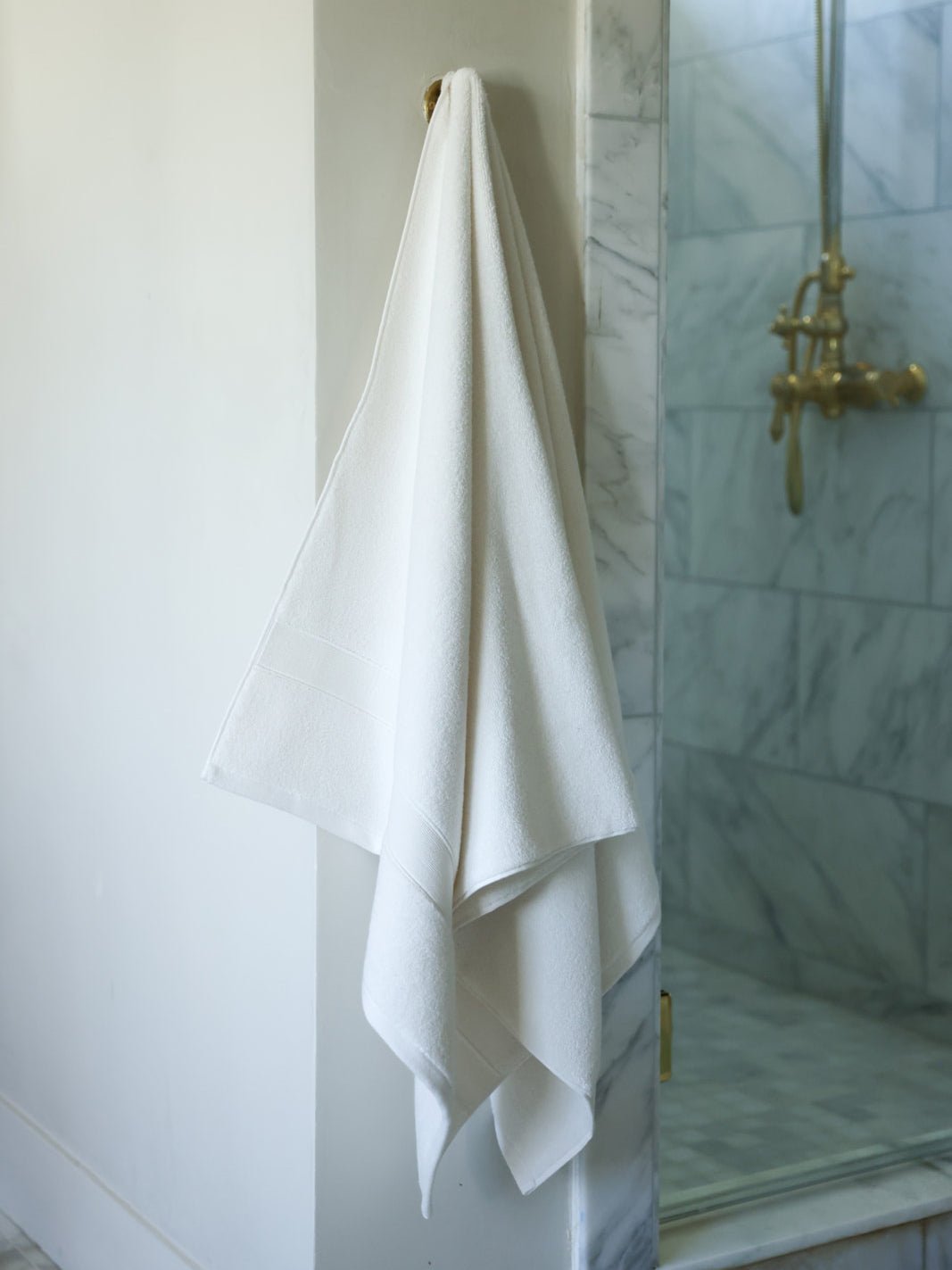 Seashell luxe bath sheet hanging next to shower 