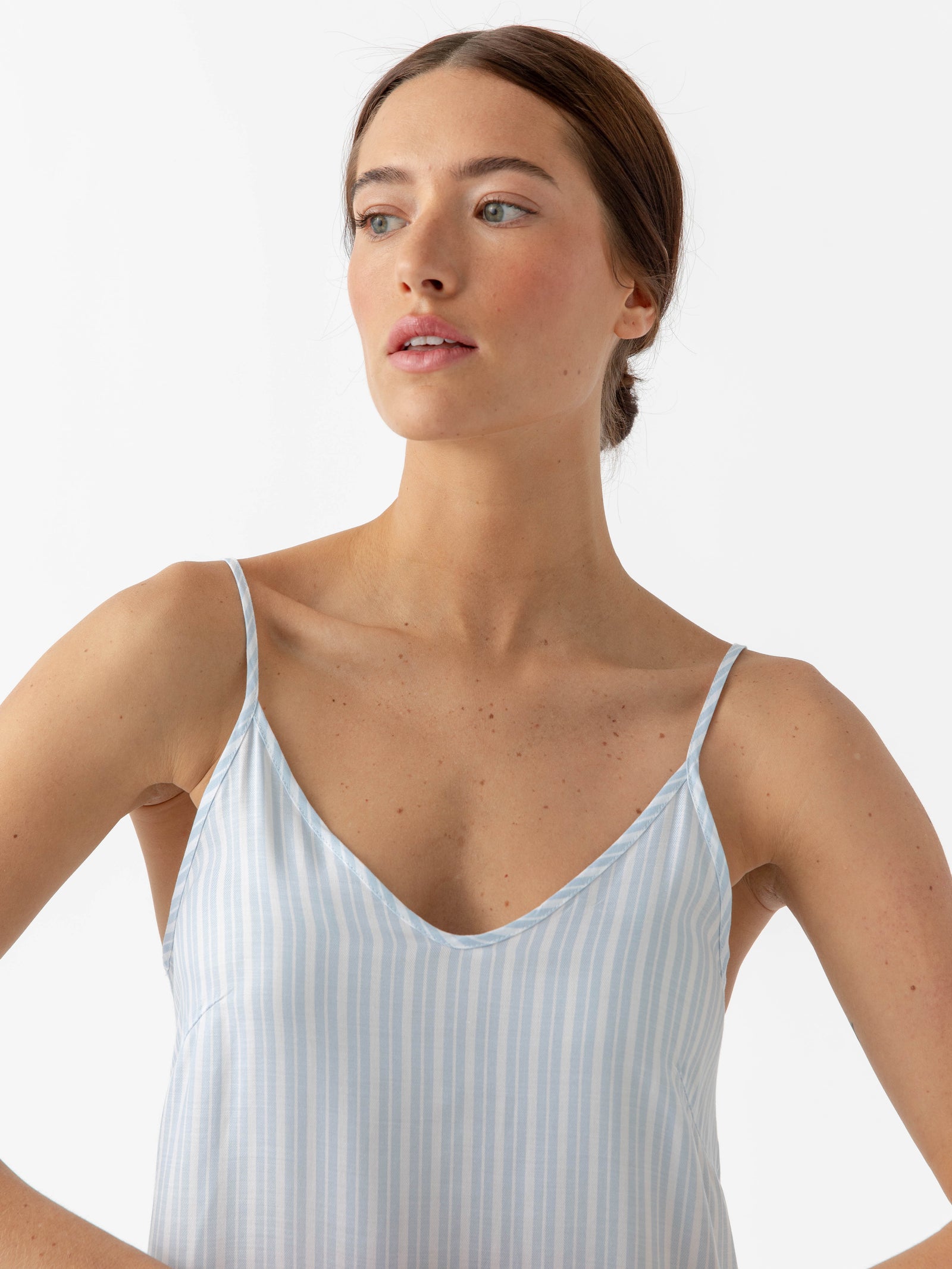 Woman photographed from torso up in Spring Blue Stripe nightgown standing in front of white background 