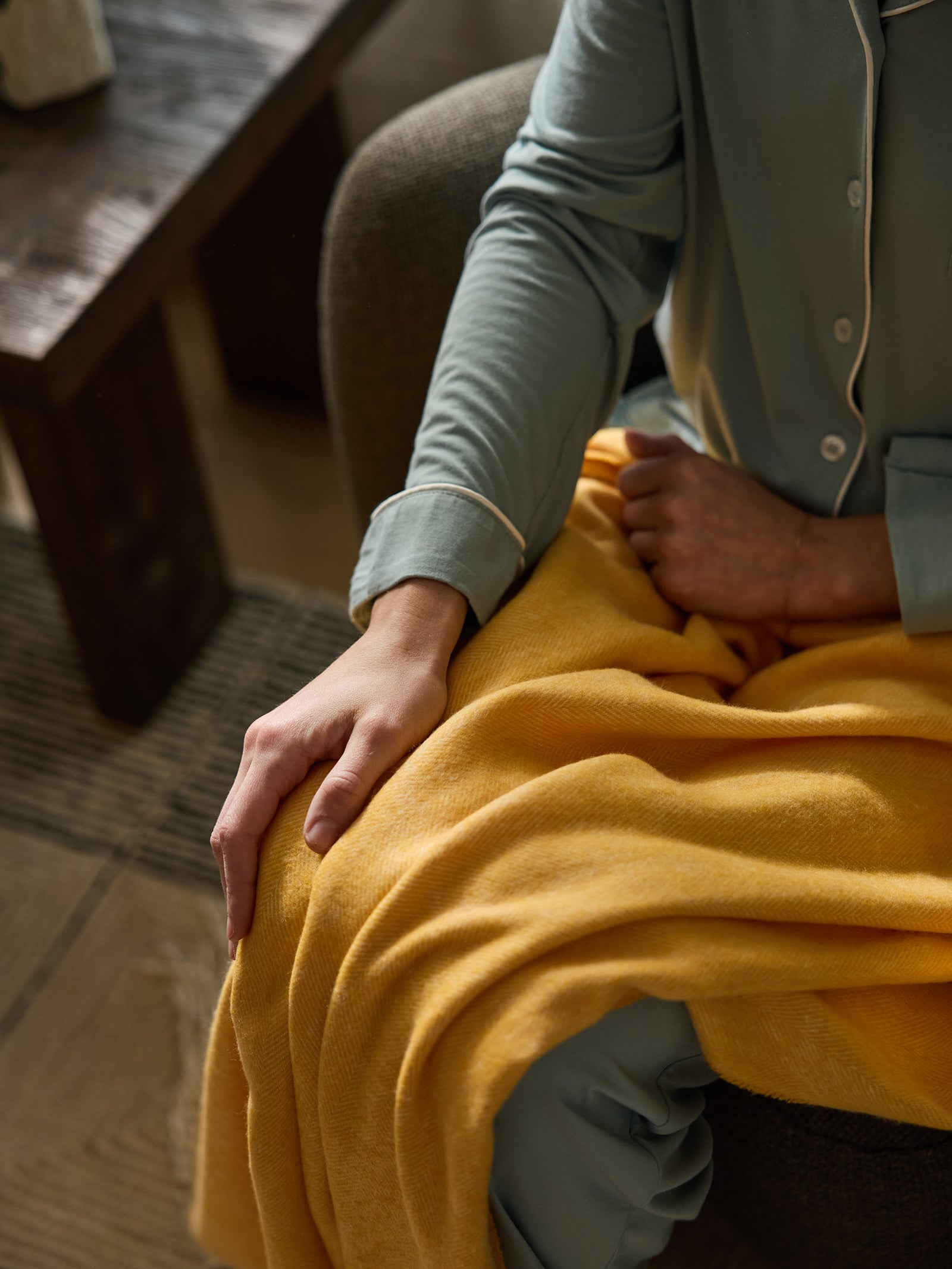 Close up of woman with sunflower herringbone tassel throw on her lap 