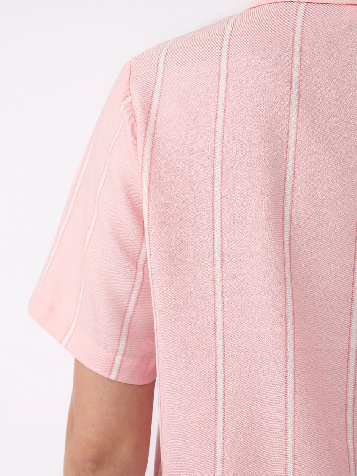 Close-up of a person wearing Cozy Earth's Women's Soft Woven Short Sleeve Pajama Top, featuring light pink with vertical white pinstripes, focusing on the back and shoulder area against a plain white background. 