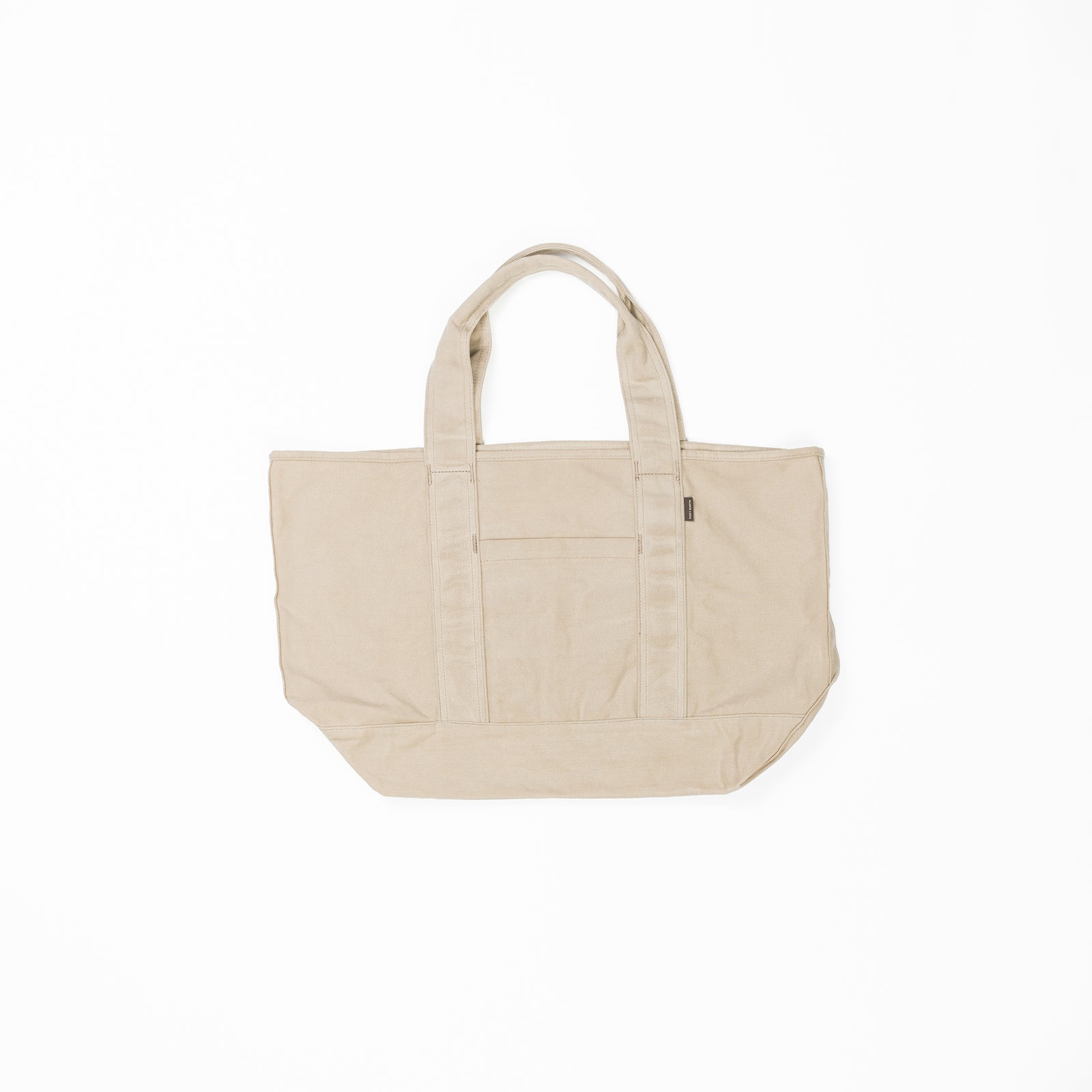 A large, beige Waxed Canvas Tote by Cozy Earth is displayed against a white background. The tote bag has two sturdy handles and features an outer pocket on the front. 