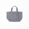 The Waxed Canvas Tote by Cozy Earth is a plain gray bag featuring double handles and a central exterior pocket. Crafted from durable fabric, it is displayed against a white background in the photograph. |Color:Washed Navy
