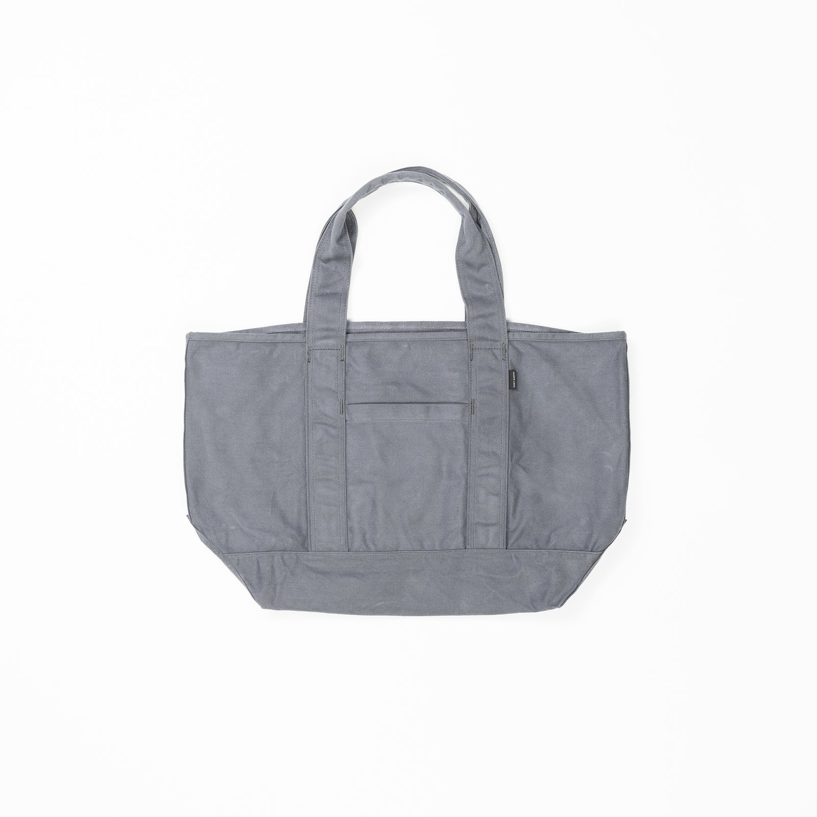 The Waxed Canvas Tote by Cozy Earth is a plain gray bag featuring double handles and a central exterior pocket. Crafted from durable fabric, it is displayed against a white background in the photograph. 