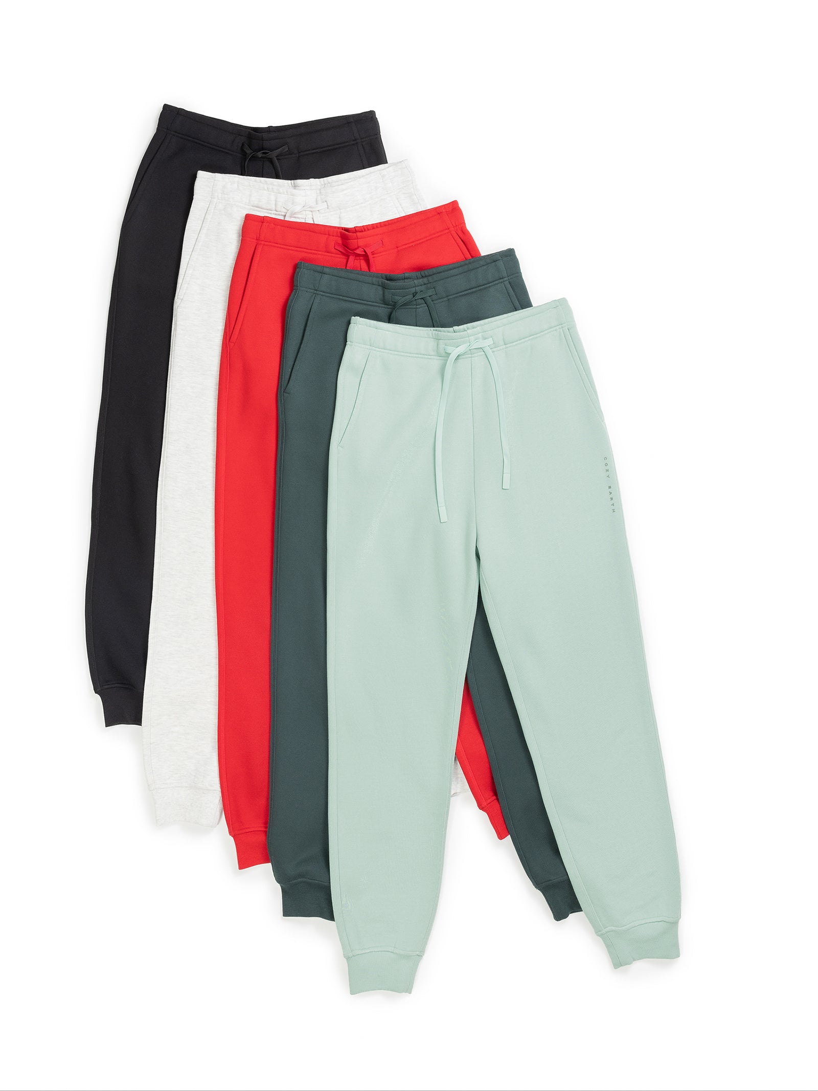 Five pairs of Men's CityScape Joggers by Cozy Earth in black, white, red, teal, and mint green are neatly stacked to display their color variety. Each jogger features drawstrings and elastic cuffs, arranged against a white backdrop. 