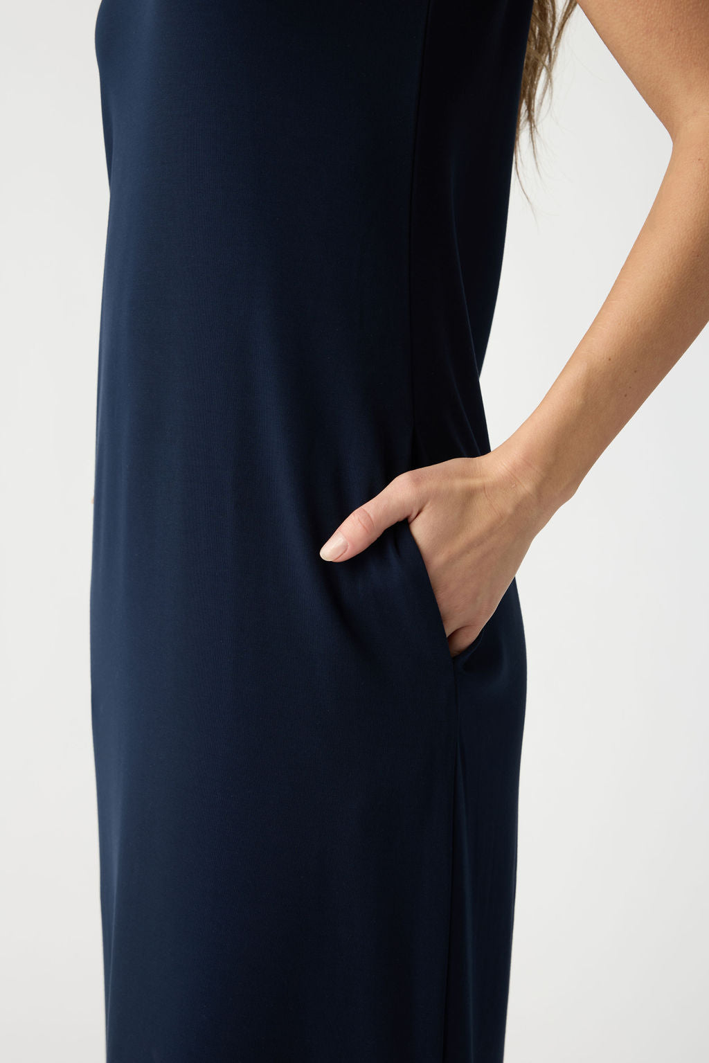 A person is shown in side profile wearing the Cozy Earth Women's Brushed Bamboo Sleeveless Midi Dress in dark blue, with a hand tucked into the dress's pocket against a plain light-colored background. 