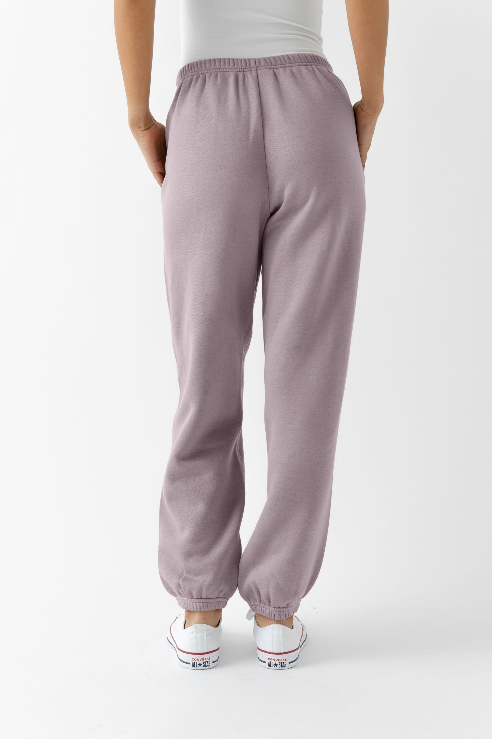 Dusty Orchid CityScape Joggers. The Joggers are being worn by a female model. The photo is taken from the waist down with the models hands in the pockets of the joggers. The back ground is white. 