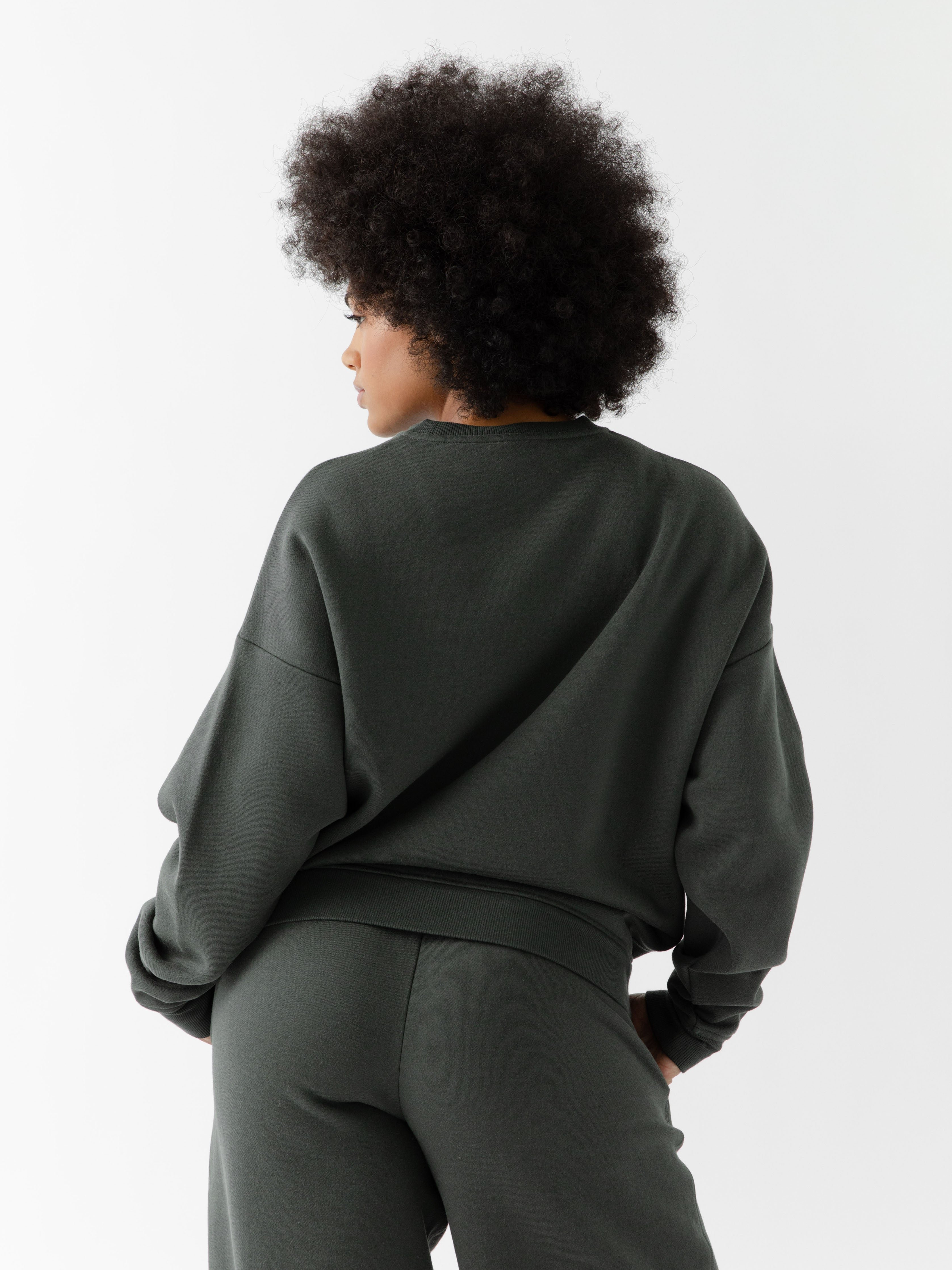 Storm CityScape Pullover Crew. The Pullover is being worn by a female model. Accompanying city scape clothing is being worn to complete the look of the outfit. The photo was taken with a white background. 