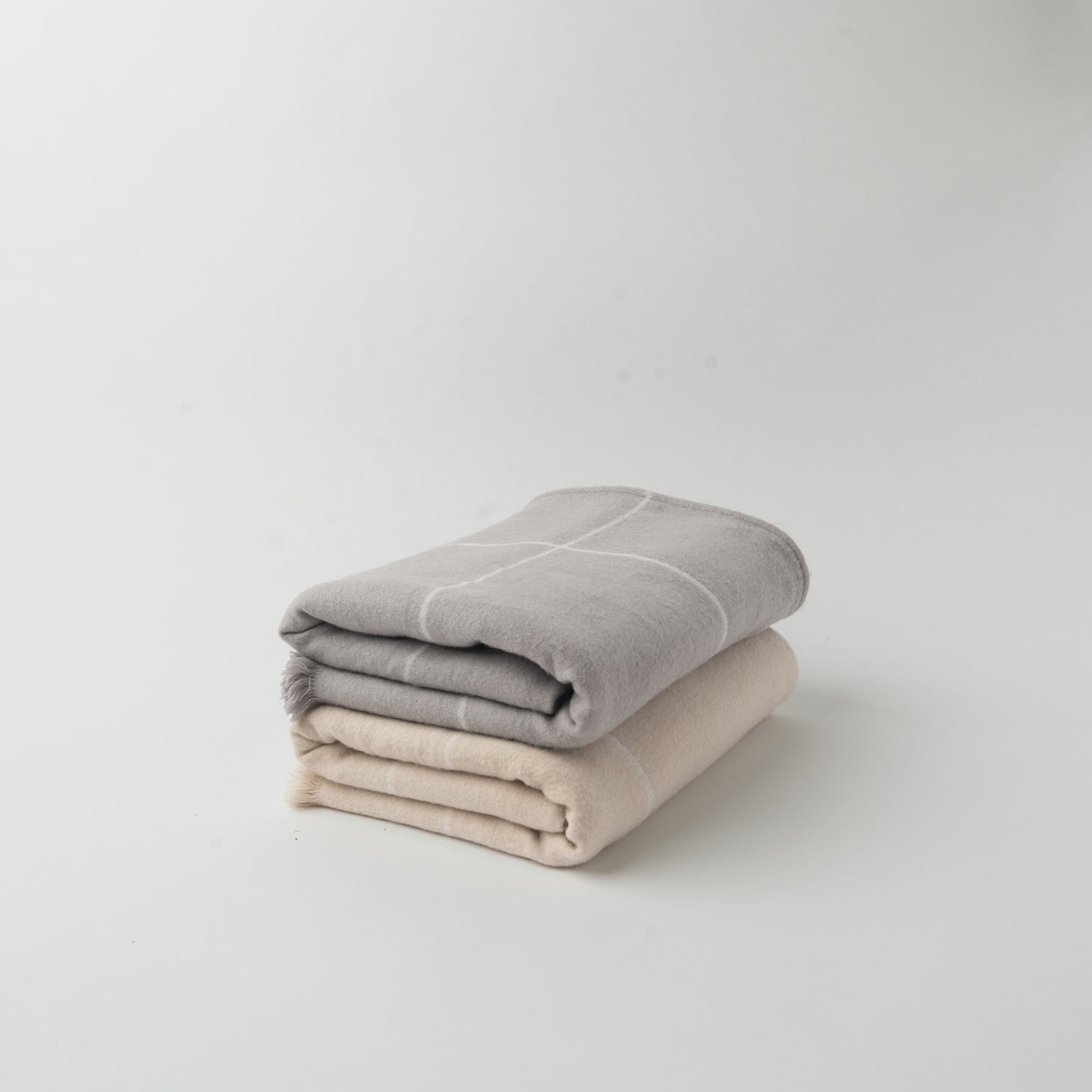 Dove Grey/Light Grey and Beige/Creme windowpane blankets folded with plain background