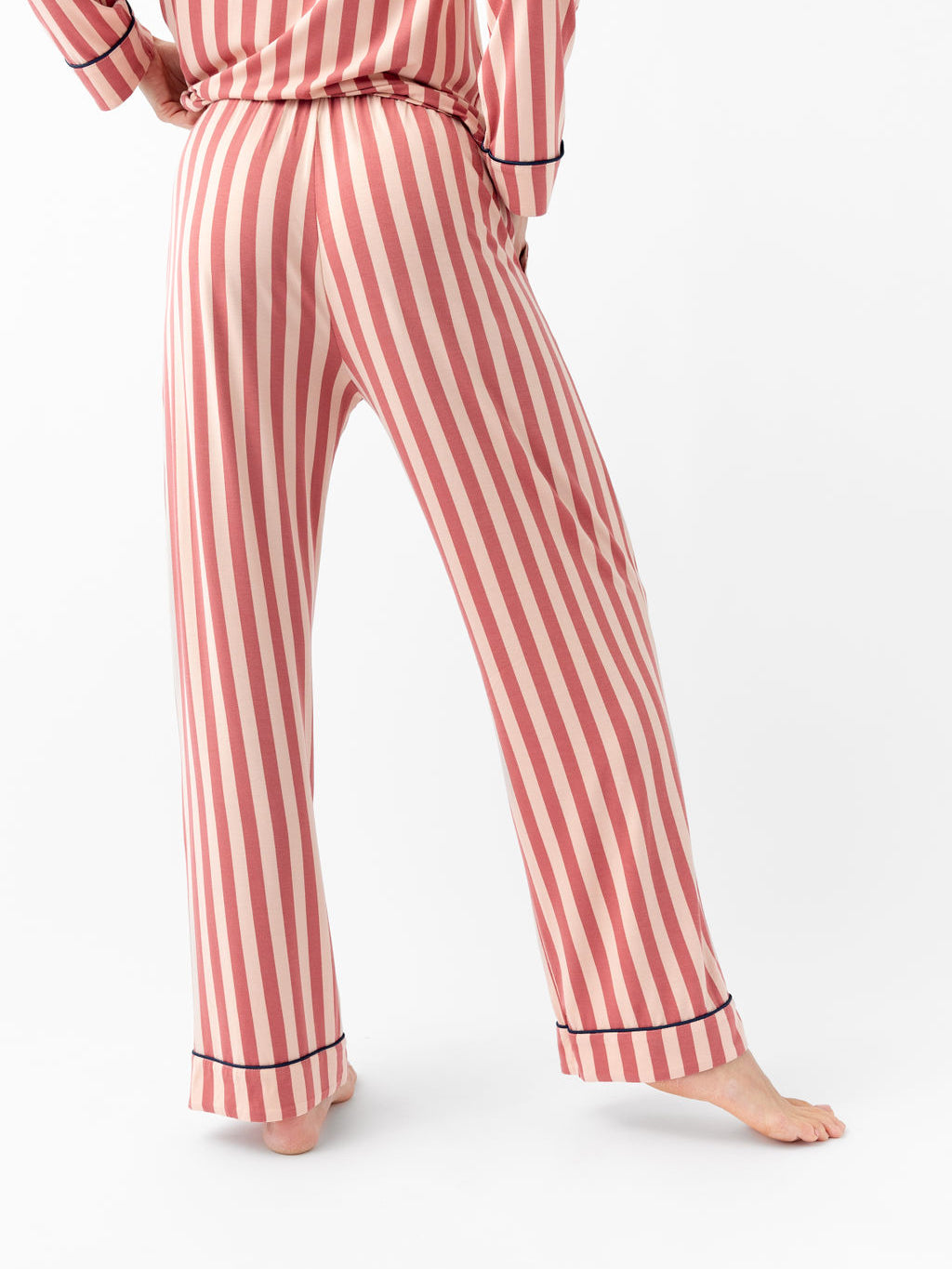 Woman wearing blush stripe pajama pants with white background 
