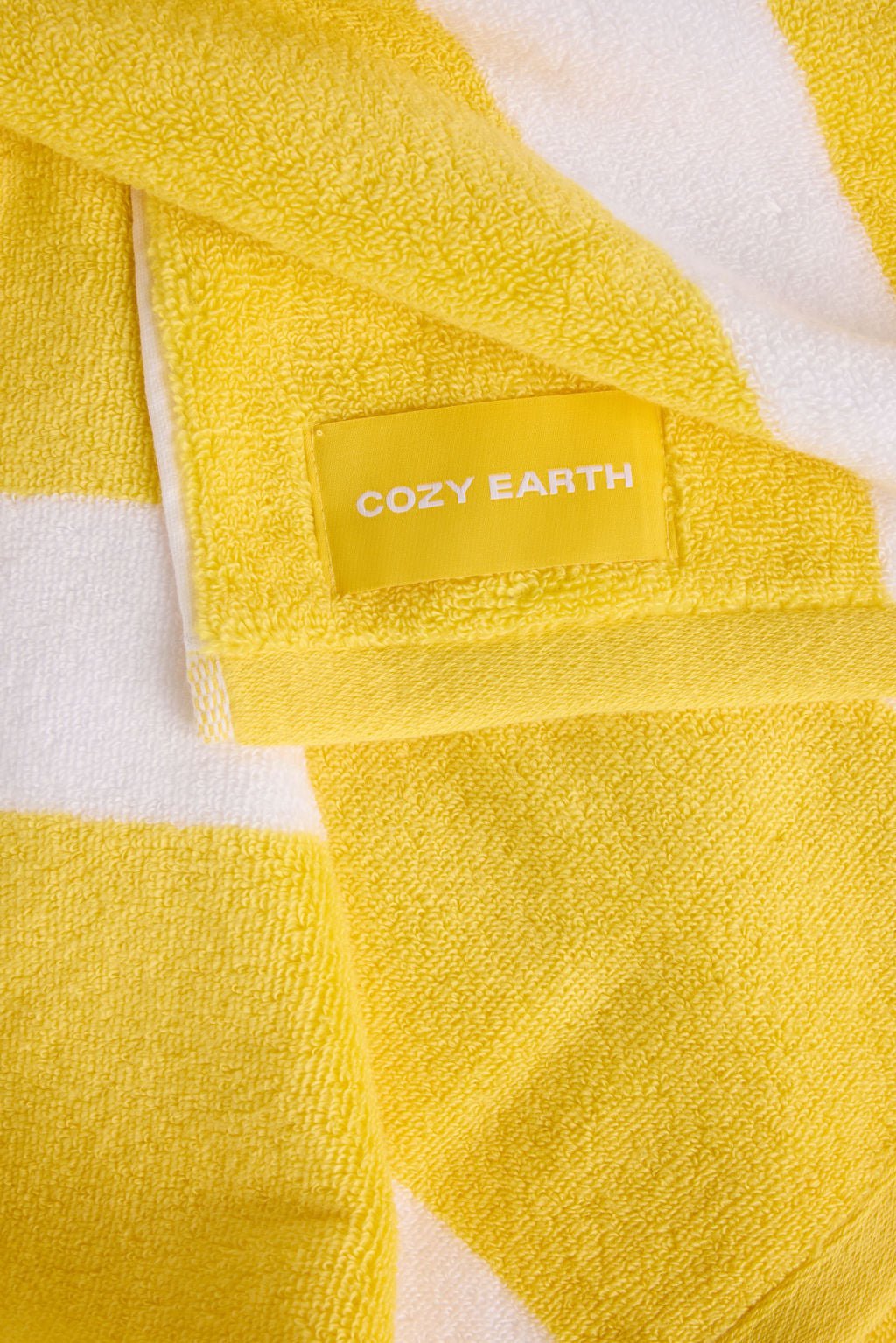 Close-up of a neatly folded Classic Stripe Resort Towel by Cozy Earth, displaying its plush texture with lemon and white stripes. 