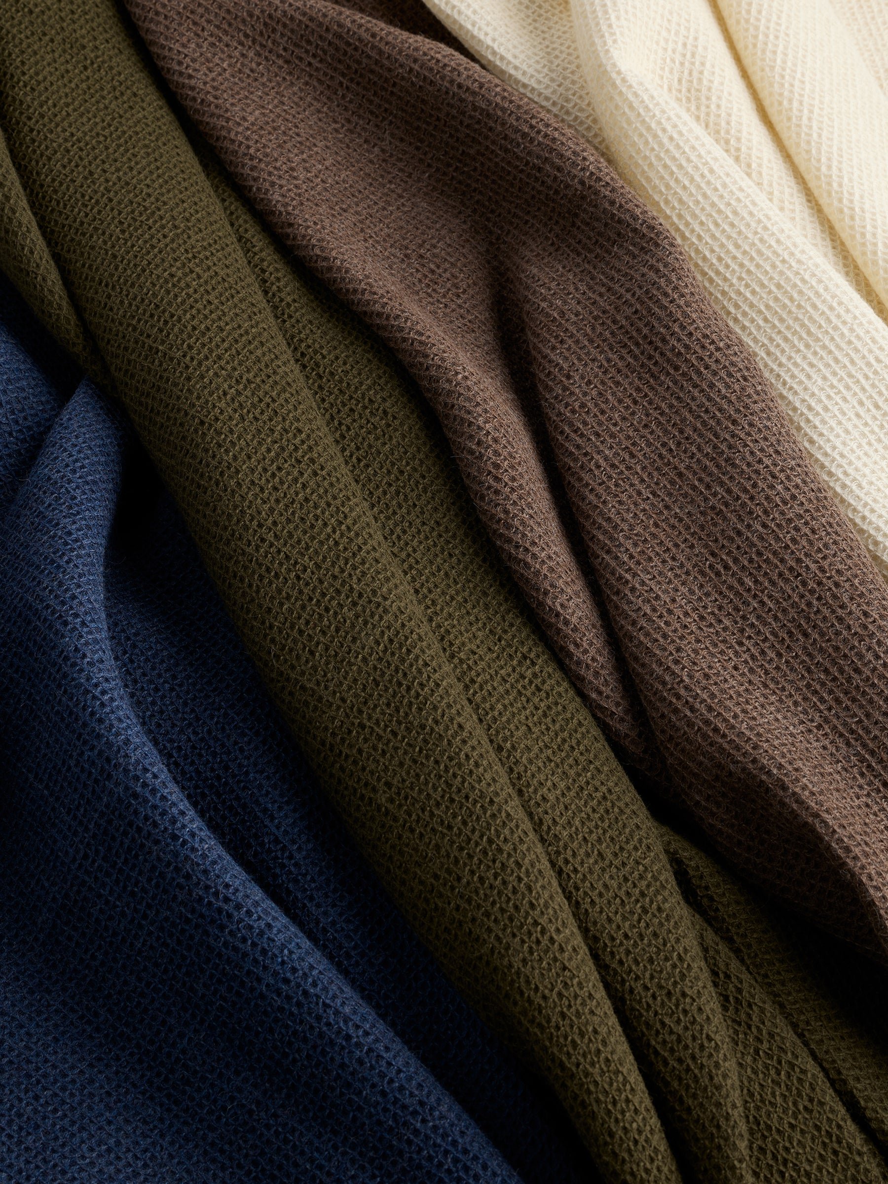 Four colors of alpaca throws laying side by side 