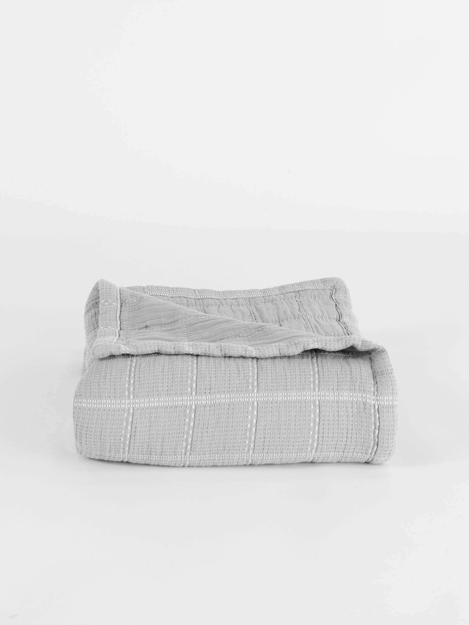 The Cozy Earth Waffle Windowpane Blanket, in light gray and featuring a knitted, subtle checkered pattern, is neatly placed on a plain white background. 