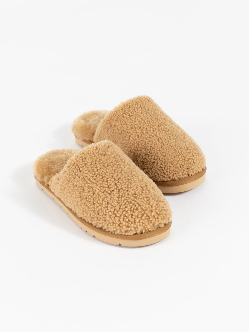 A pair of Puffy Sheep Slippers by Cozy Earth, featuring a cozy tan design with a fuzzy, textured exterior and soft interior, crafted in a slip-on style with rubber soles, set against a plain white background.