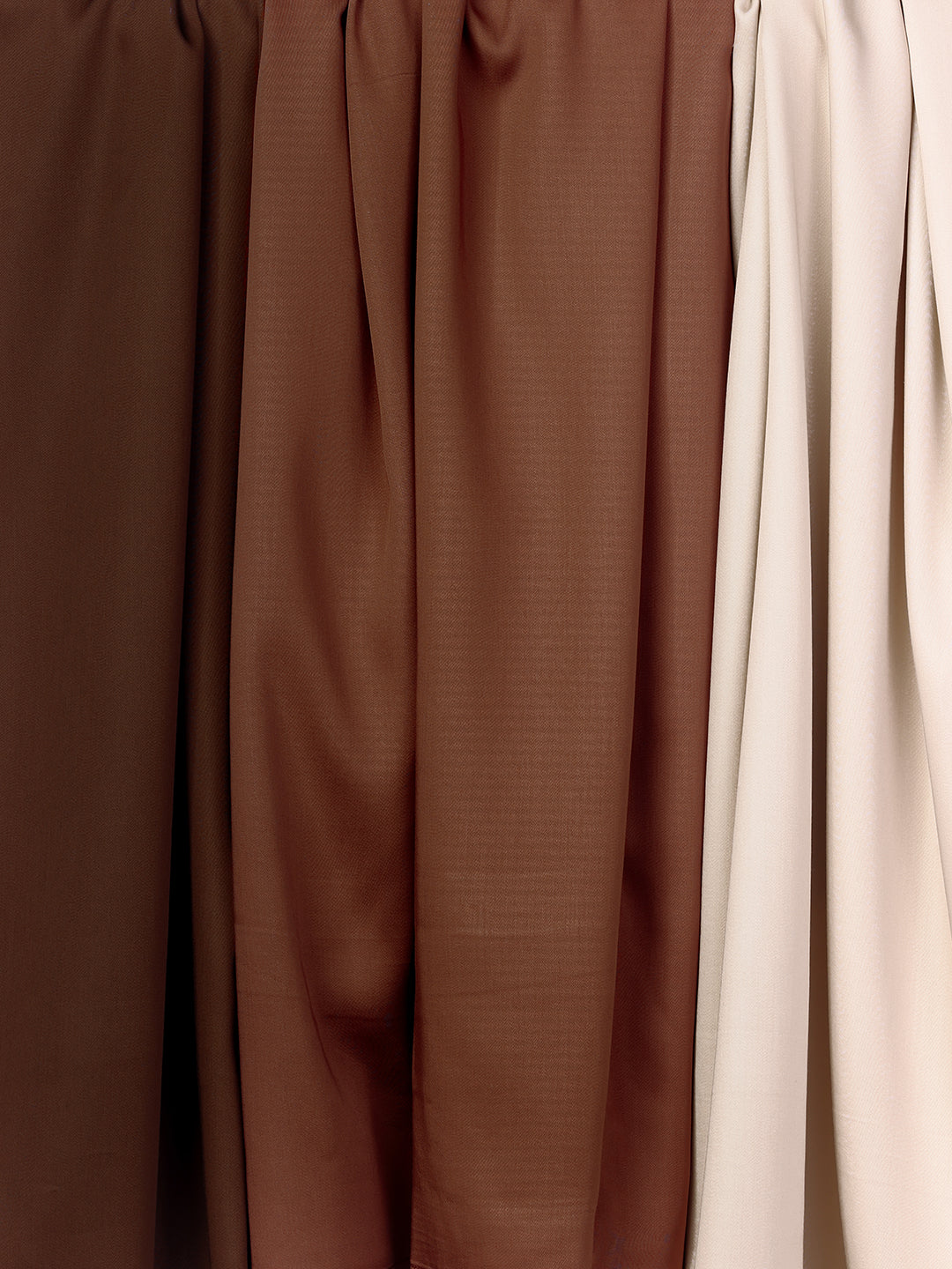 Four swatches of the Bamboo Sheet Set by Cozy Earth are displayed side by side, with colors ranging smoothly from a deep brown on the left to a light beige on the right. 