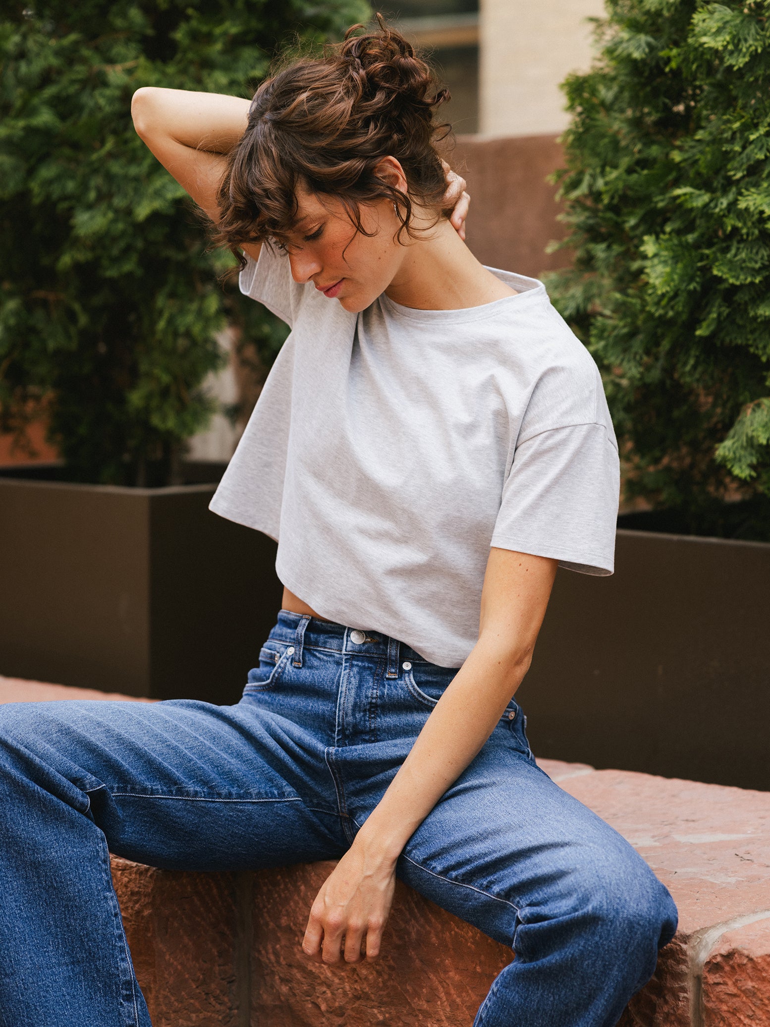 French Dove Heather All Day Cropped Tee. The photo of the All Day Cropped Tee is taken with a with a city background and is worn by a woman. 