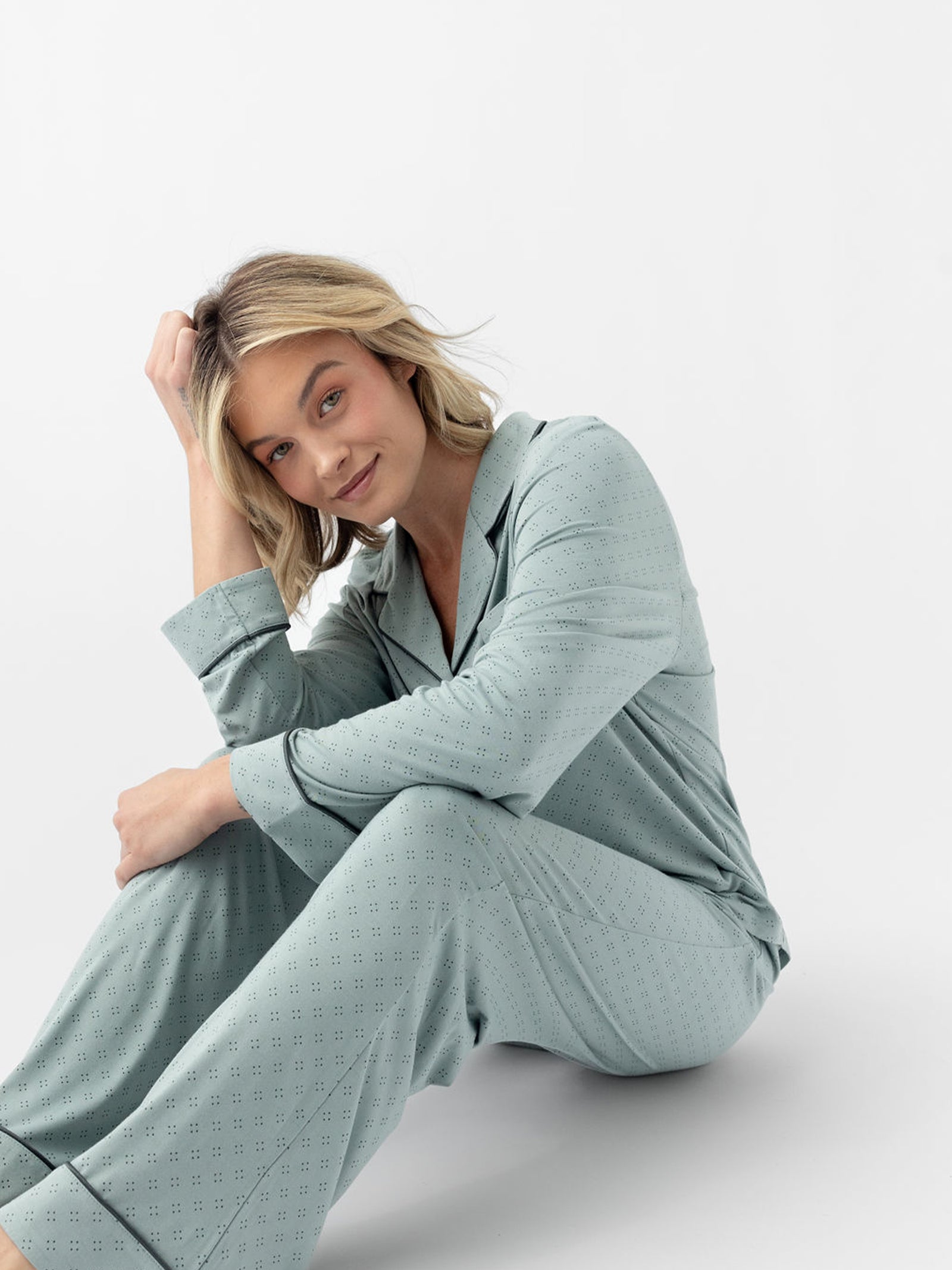 Woman sitting on floor wearing haze diamond dot pajamas with white background 